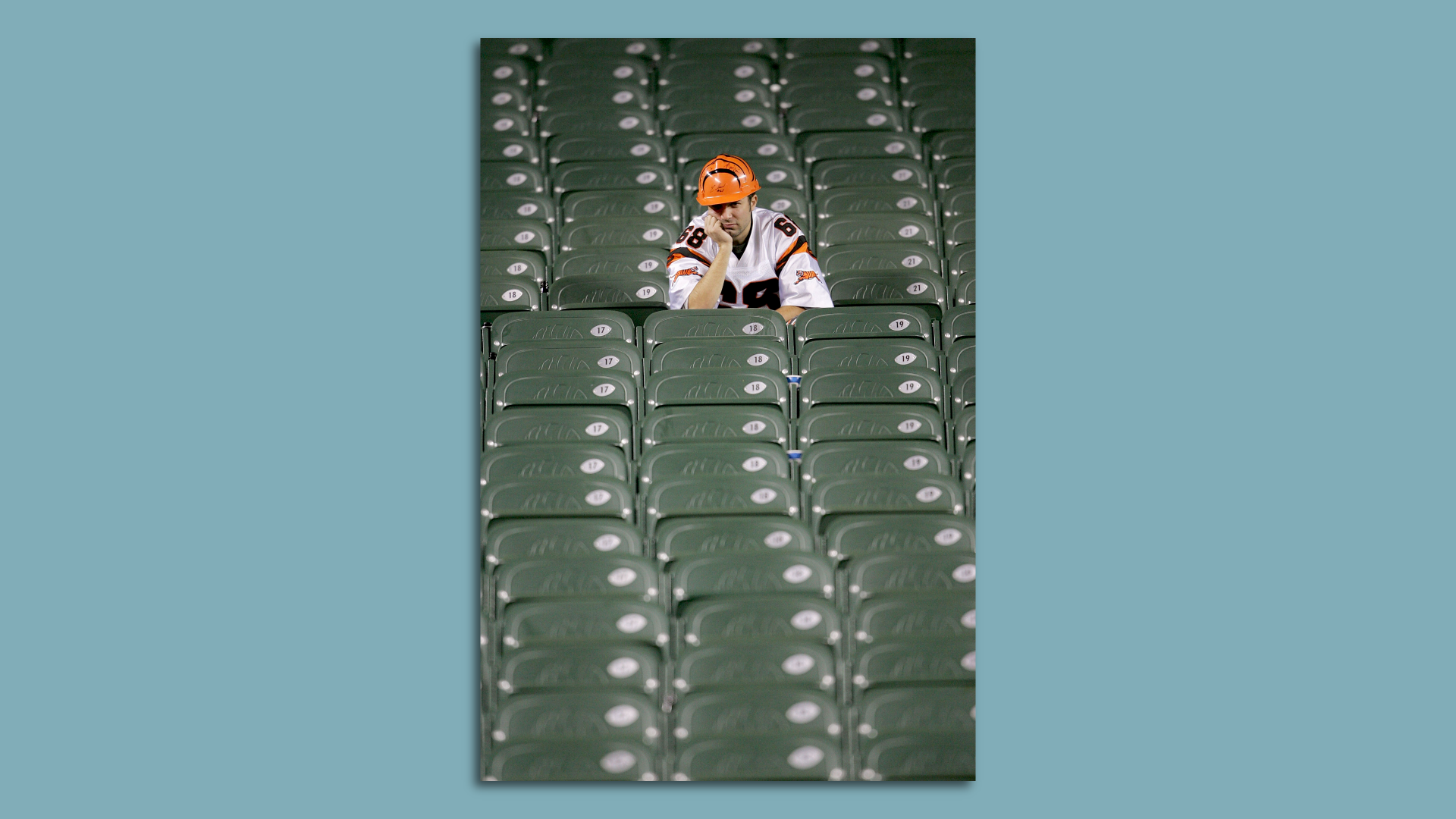 A sad Cincinnati Bengal fan sits alone in a stadium.