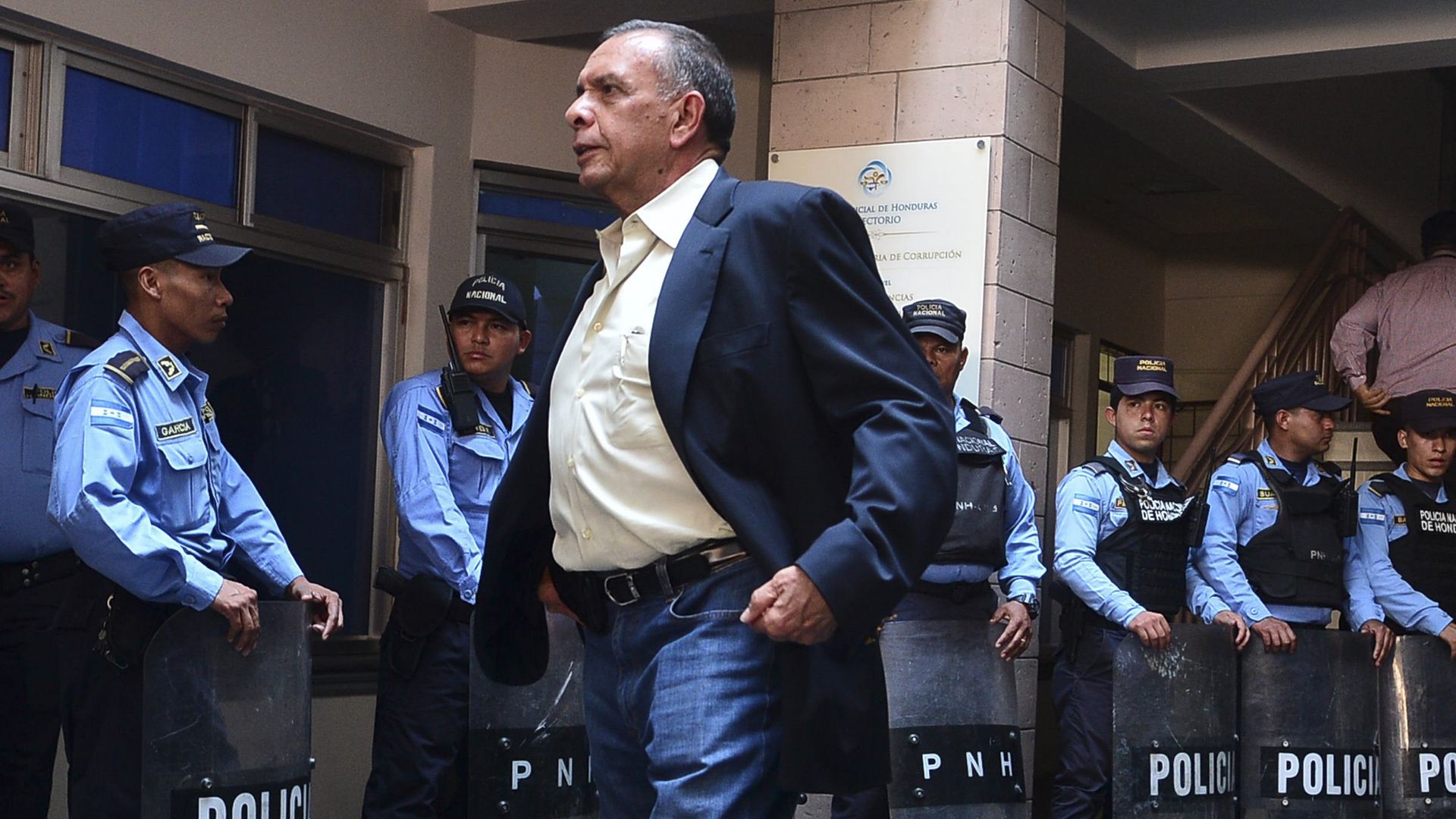 Honduras' former president Porfirio Lobo Sosa walks in front of a line of police officers in Tegucigalpa.