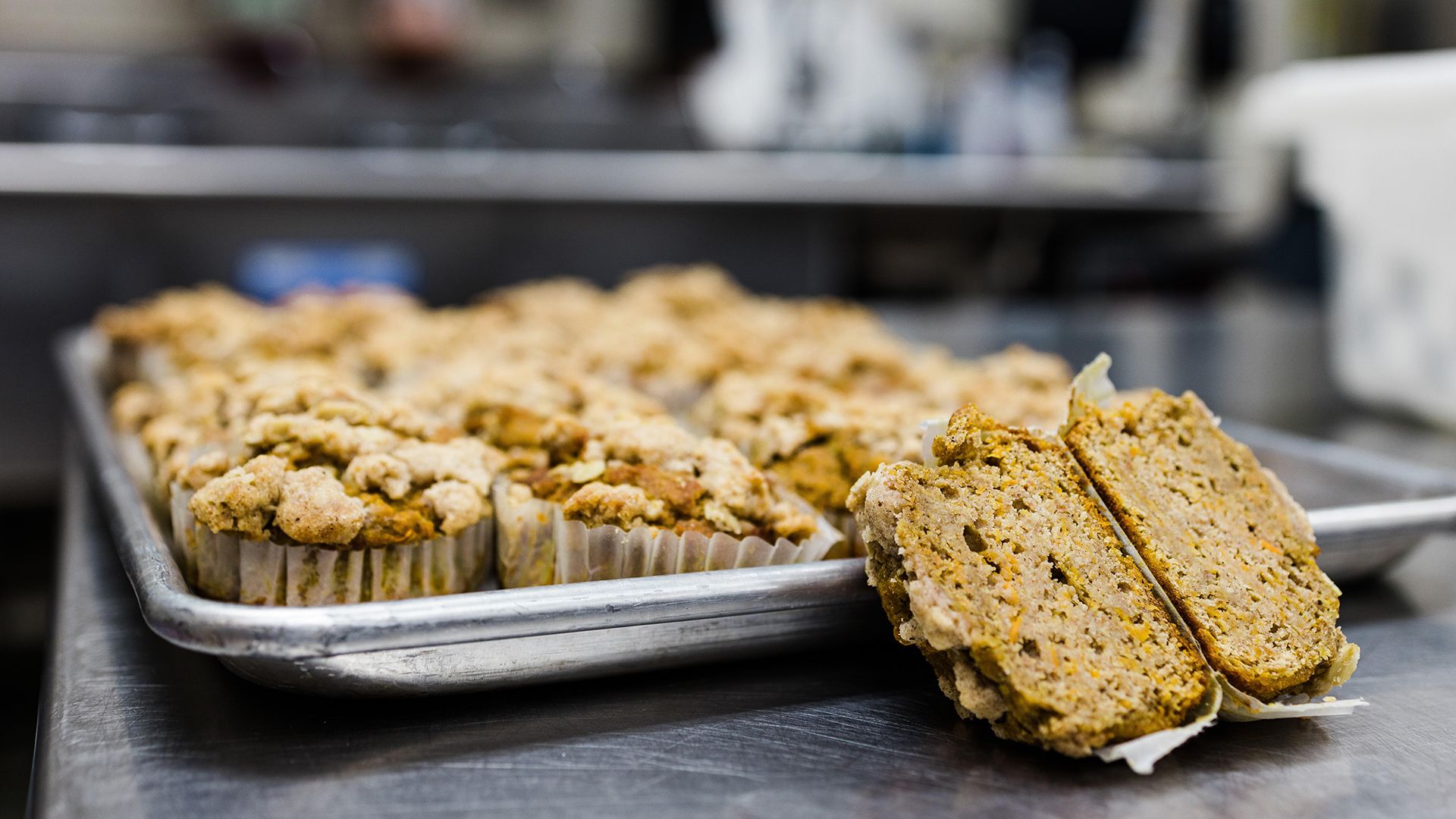 Image of some muffins on a tray, with one sliced open 