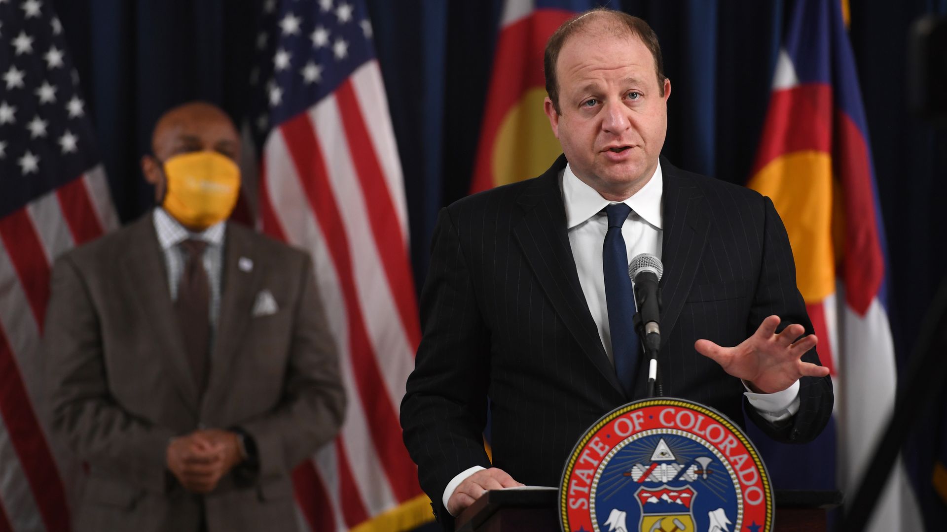 Gov. Jared Polis, front, and Denver Mayor Michael Hancock, left, announce COVID-19 restrictions in November.