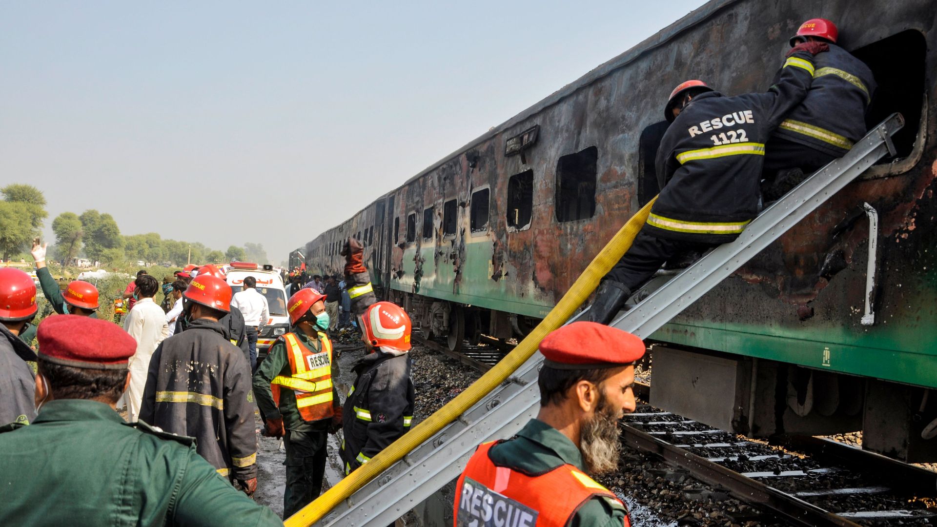 Firefighters work to cool down the burnt-out train carriages.