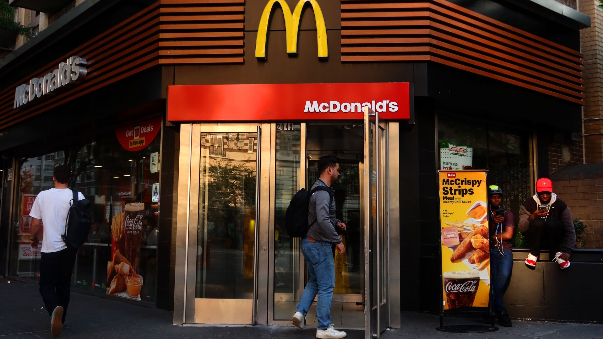 A person enters a McDonald's restaurant with a sign for McCrispy Strips in front of restaurant