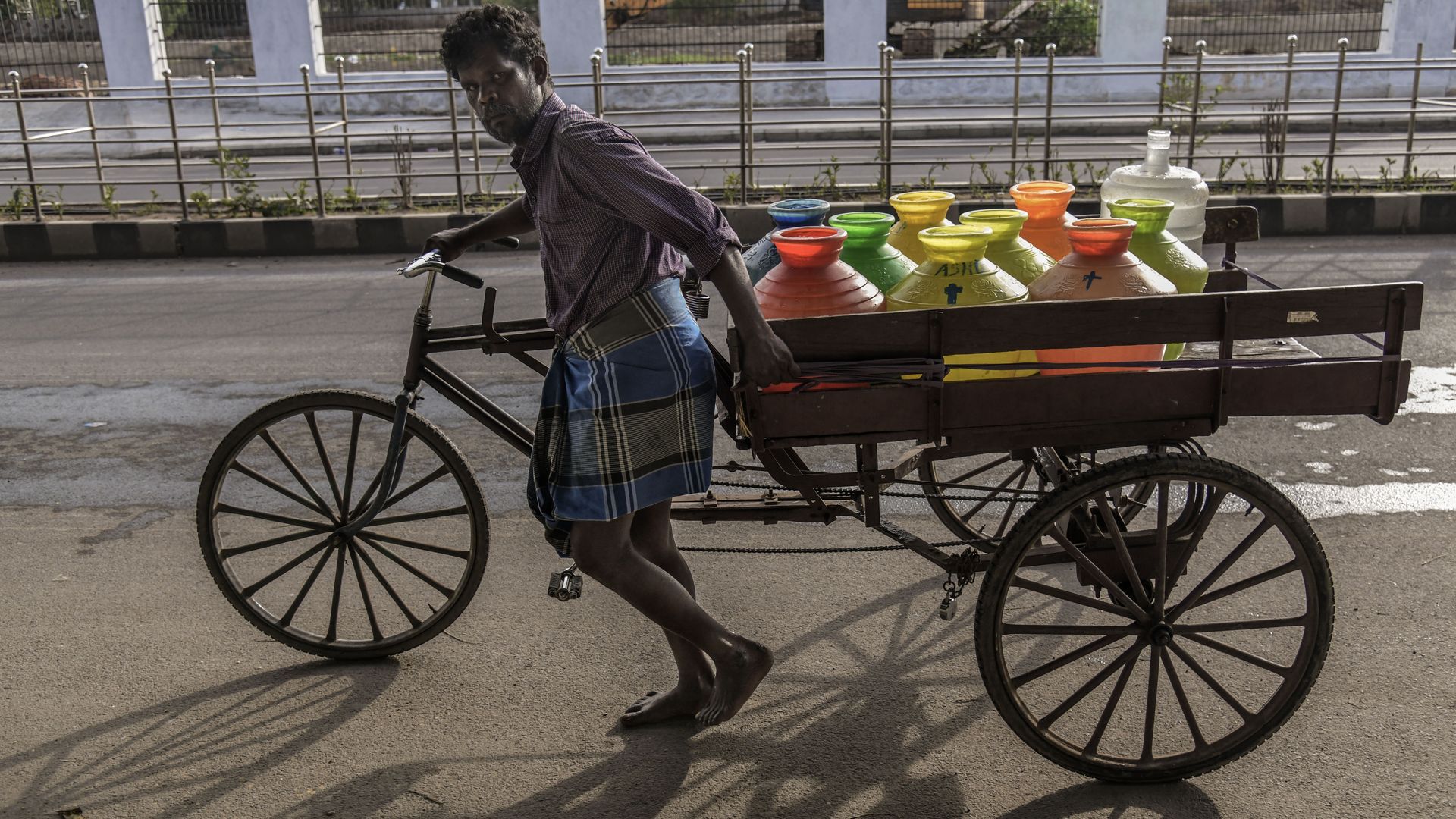 bicyclist transporting colored water cans