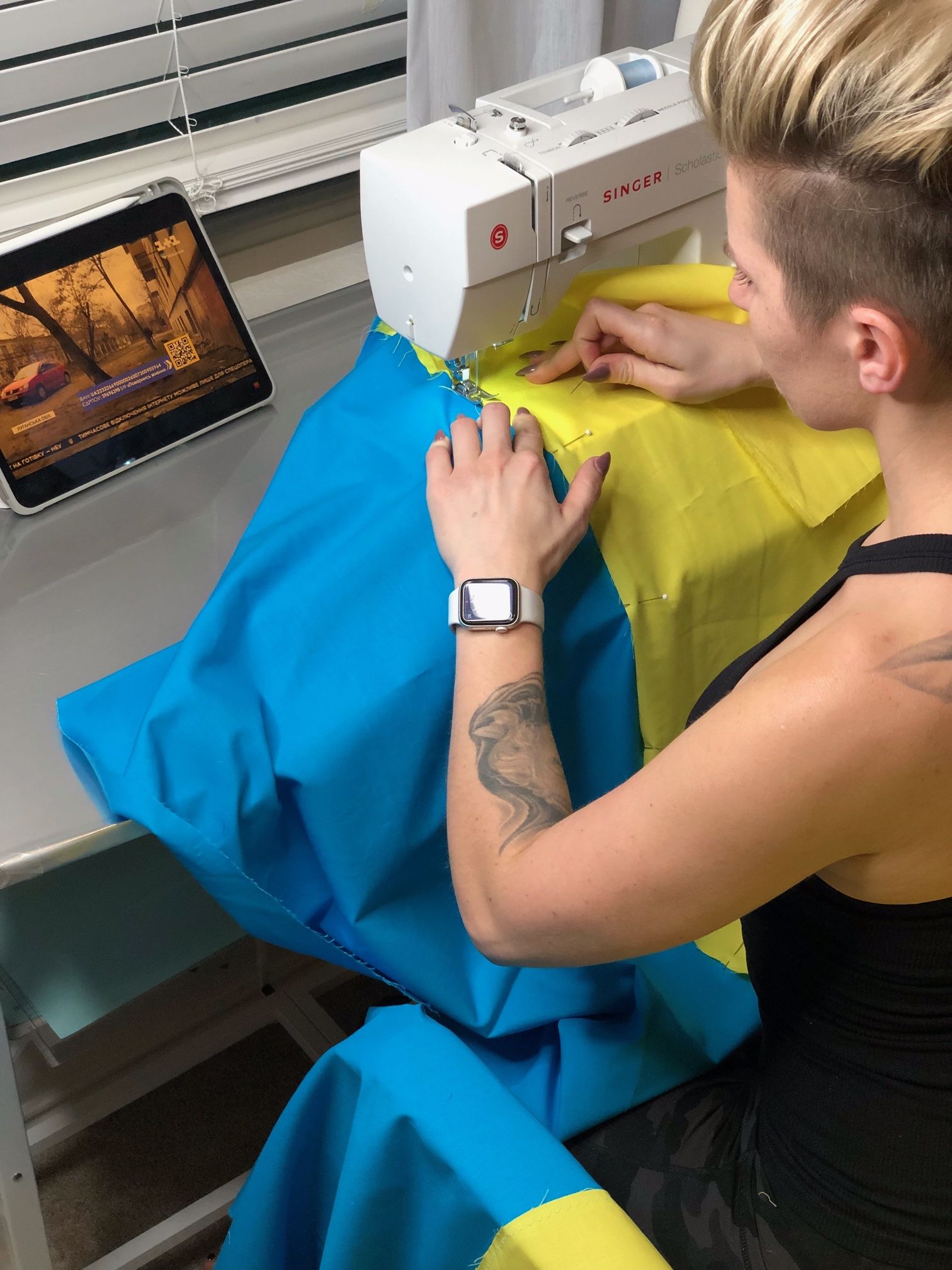 A person sews the Ukrainian flag.