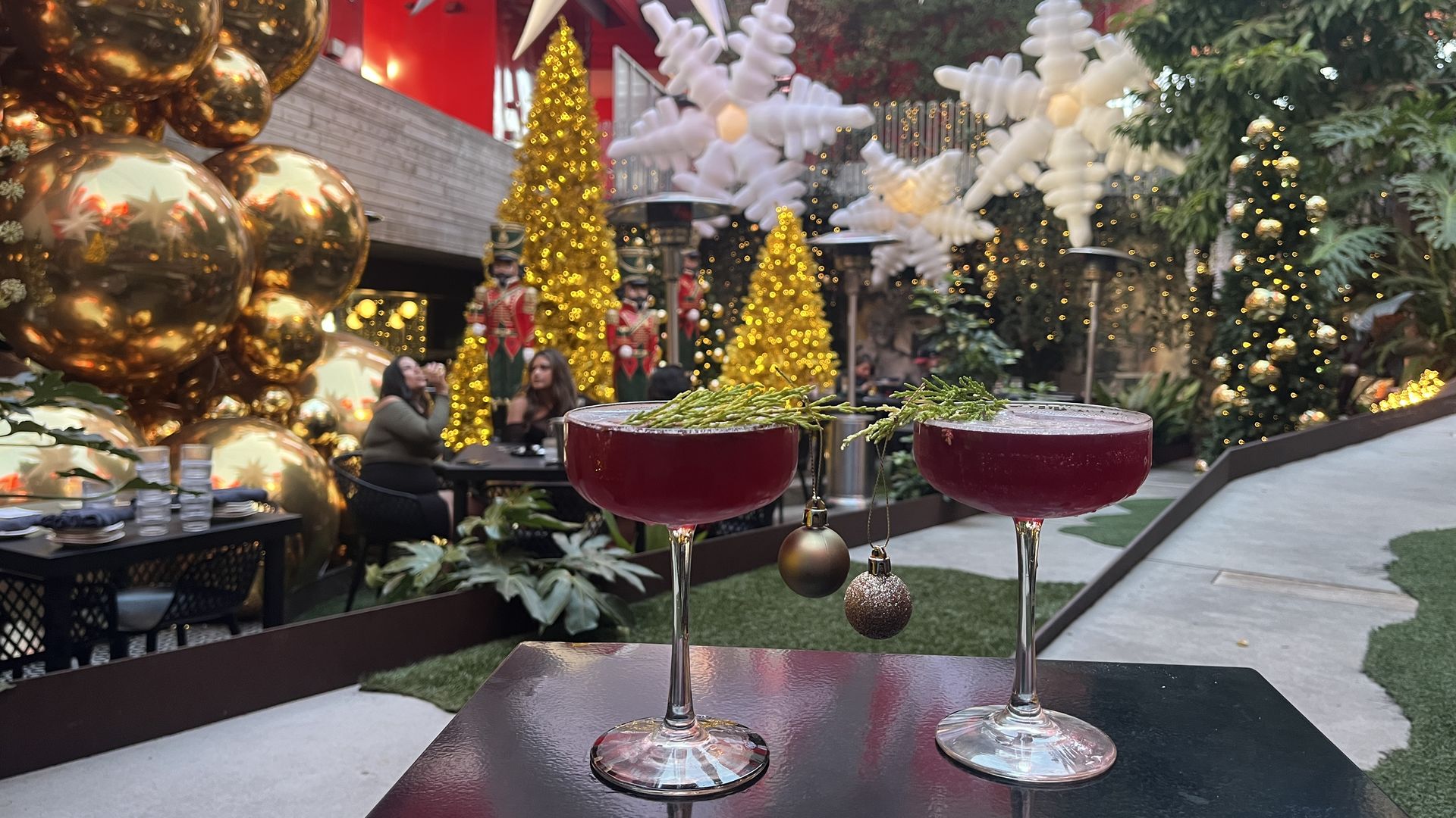 Two cocktails with ornaments hanging from them in a Christmas-themed bar. 