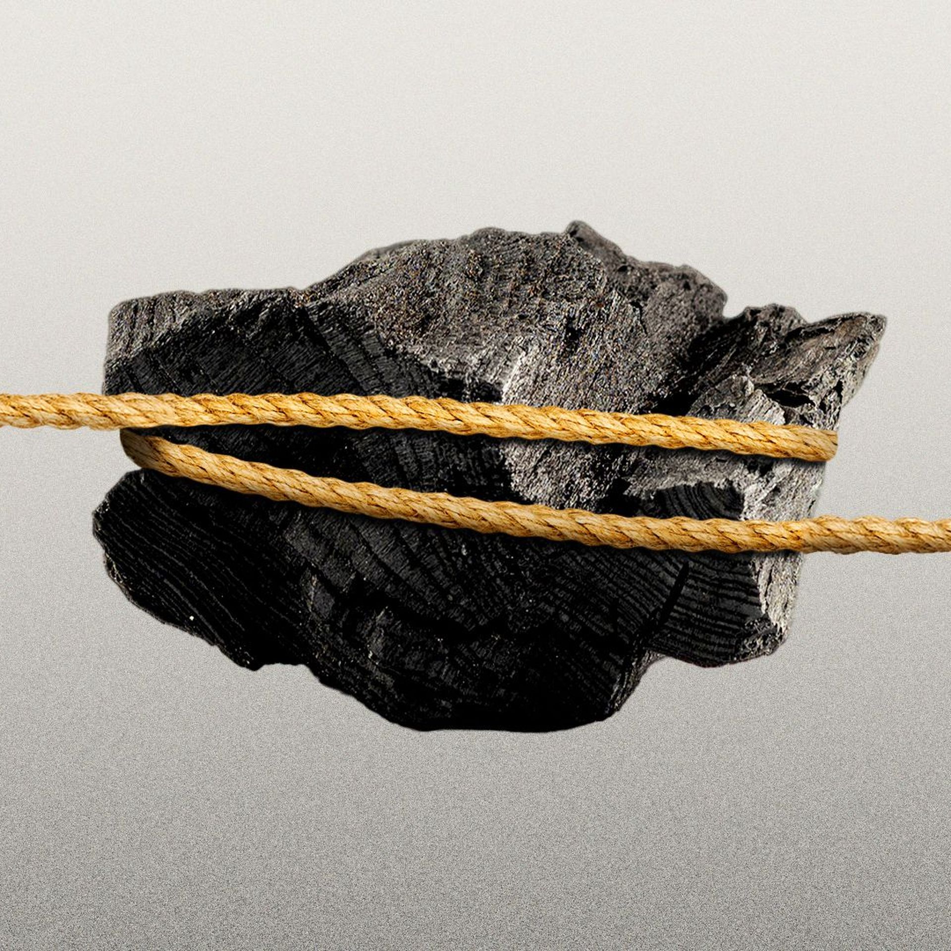 Illustration of a tug of war rope looped around a piece of coal with hands pulling on either end.