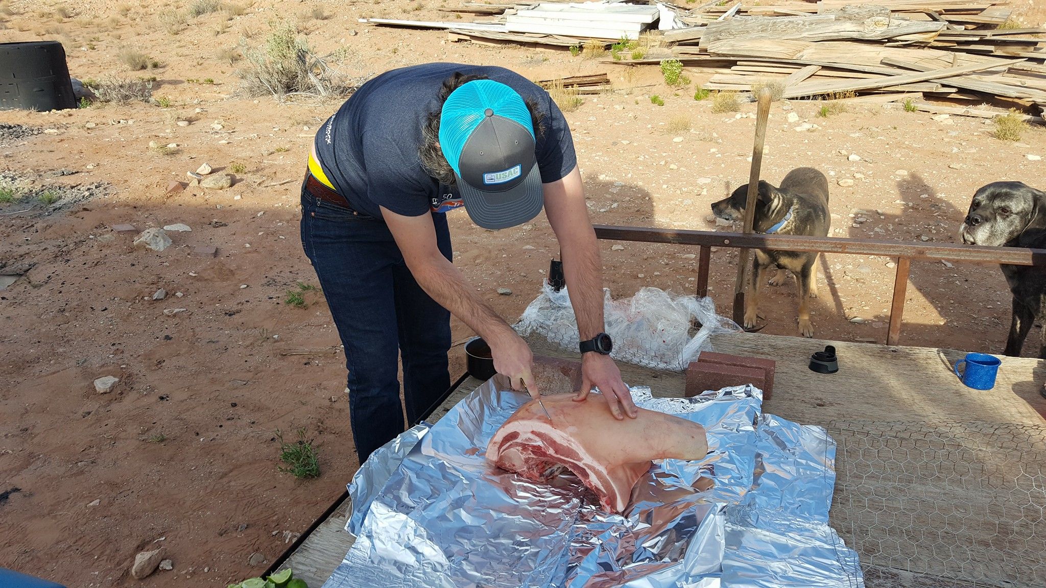 A man scores a pork shoulder on foil.