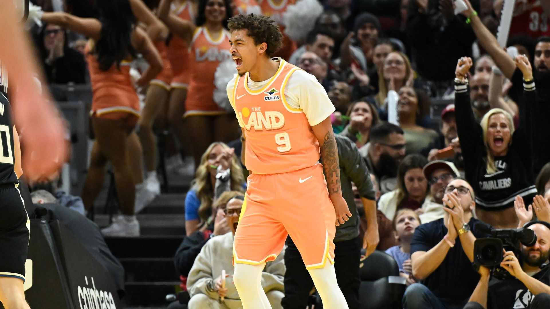 Cavs Craig Porter Jr. in a creamsicle "The Land" jersey screaming on a basketball court.