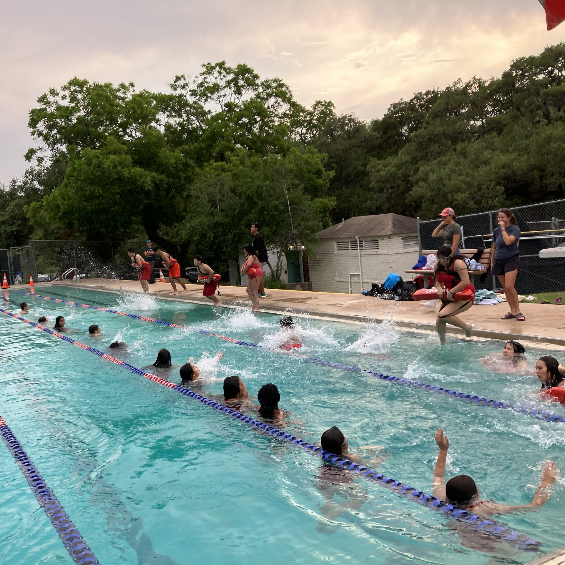 Lifeguard trainees jump into water to practice rescues during a lifeguard class at a pool in Austin. 