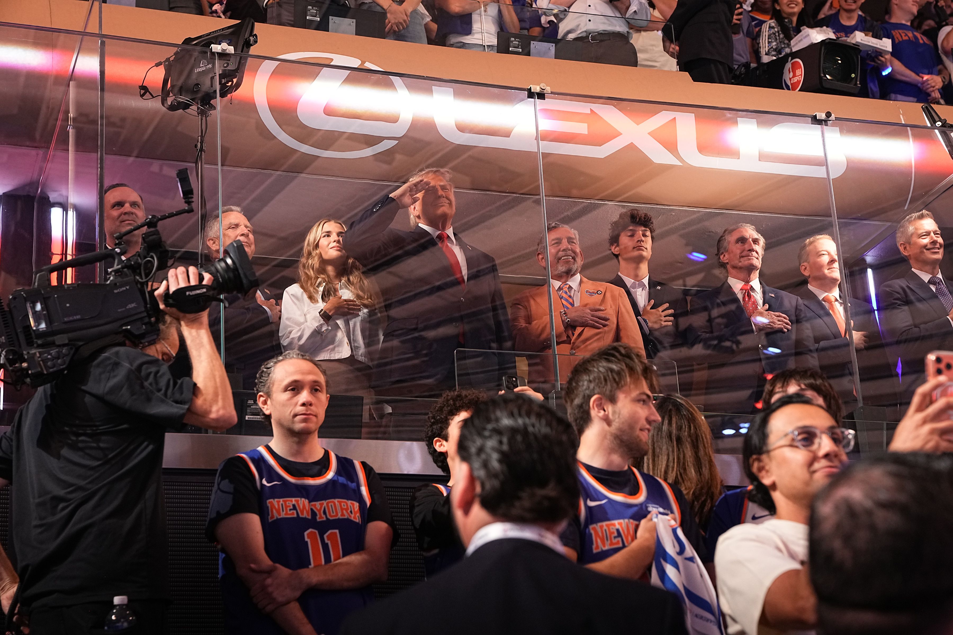 President Donald Trump, fourth from left, salutes as he stands between his granddaughter, Kai Trump, left, and James Dolan, chief executive of Madison Square Garden and the owner of the New York Knicks, during the national anthem before the start of Game 3 of the NBA Finals between the New York Knic