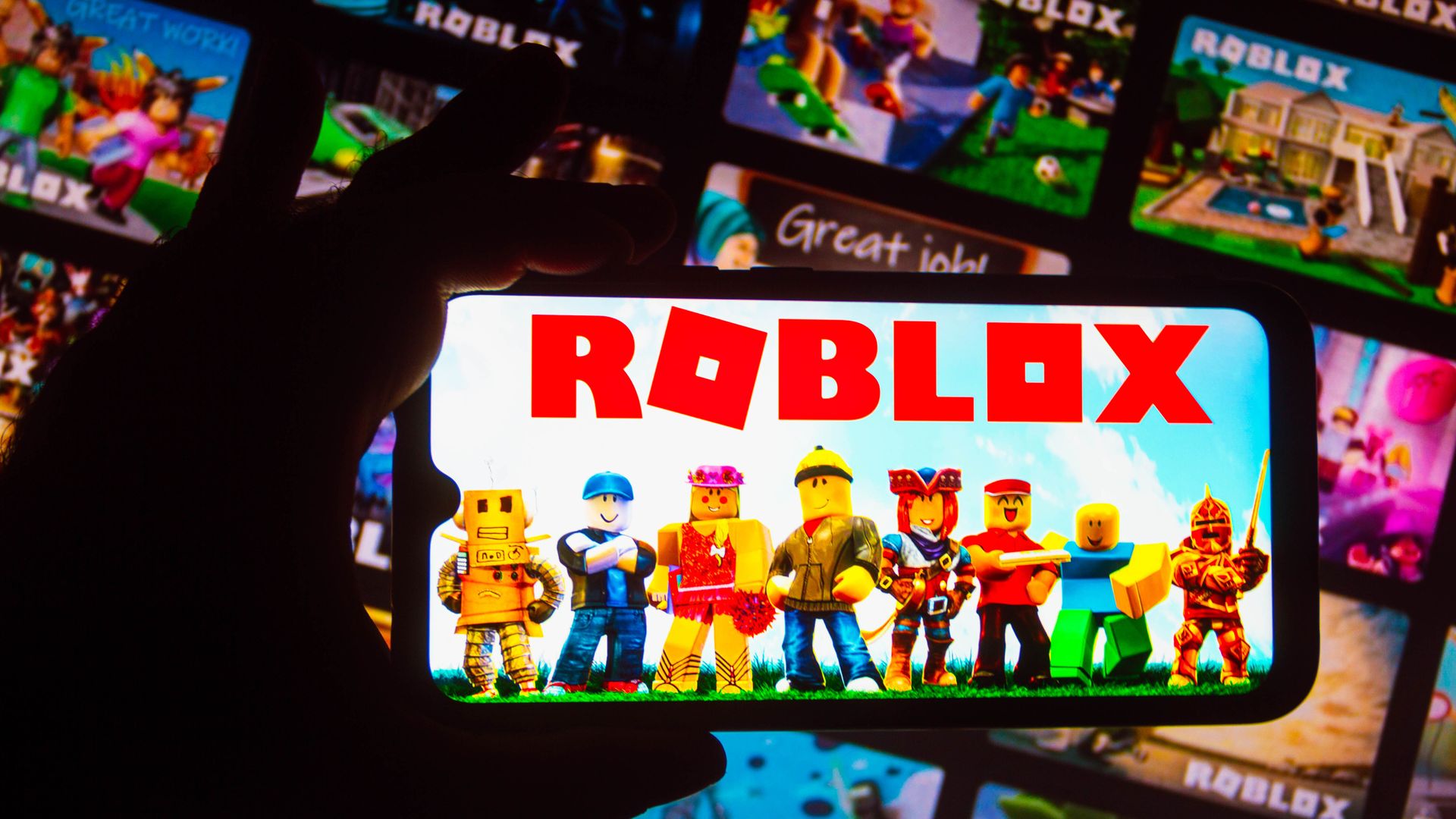Photo of a person holding a phone that is running Roblox