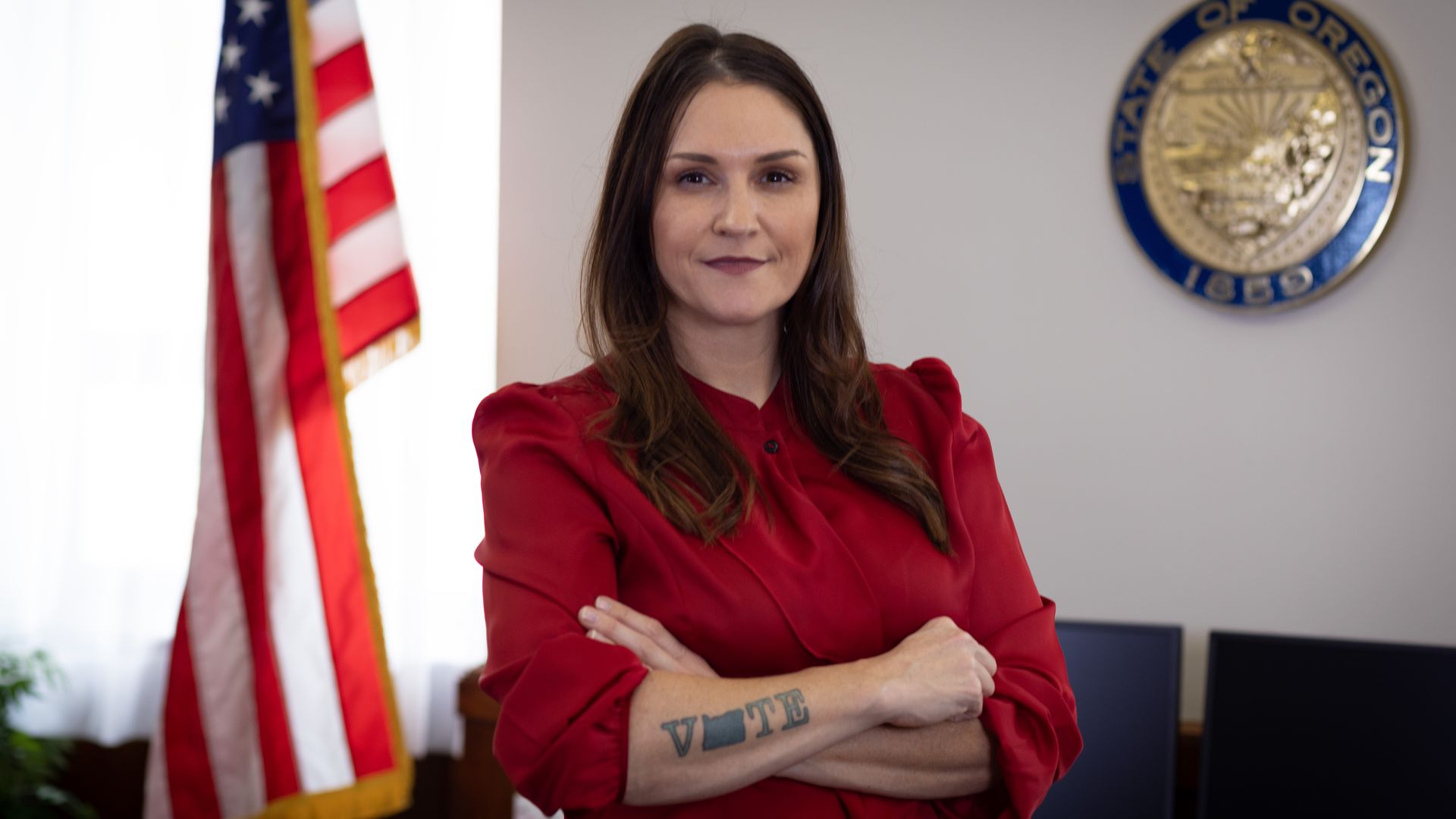 Oregon Secretary of State Shemia Fagan stands with her arms crossed.