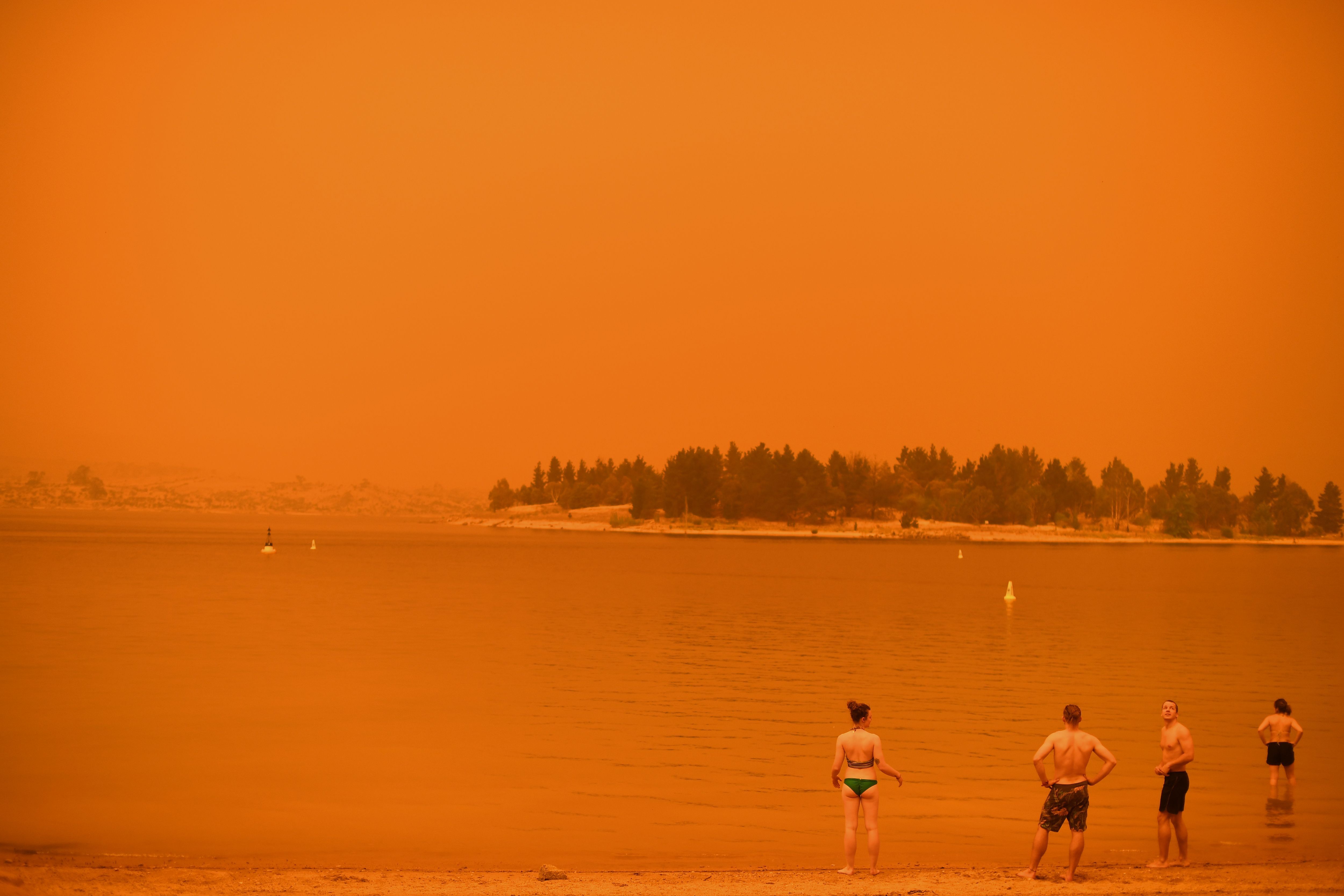  Residents take a dip to cool down at Lake Jindabyne, under a red sky due to smoke from bushfires, in the town of Jindabyne in New South Wales 