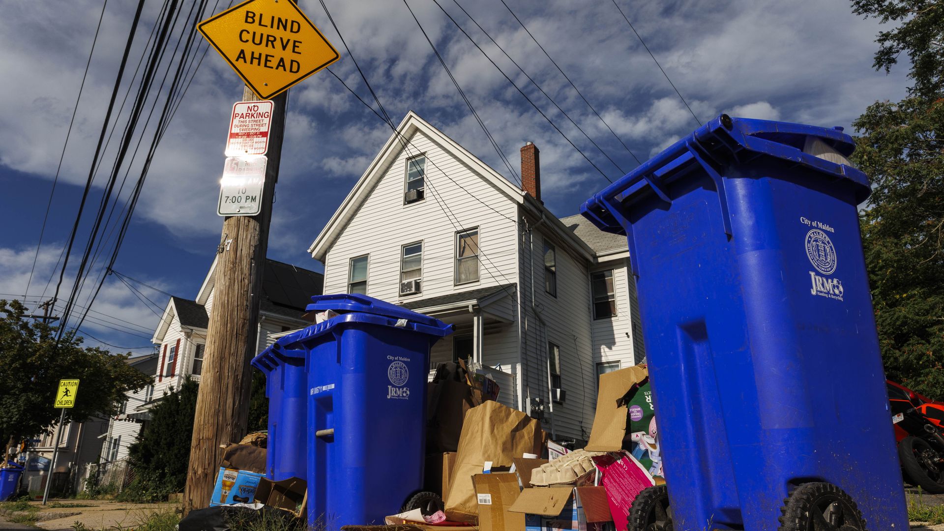 Overflowing recycling bins sit on the curb of Pearl Street in Malden on July 22, 2025. 
