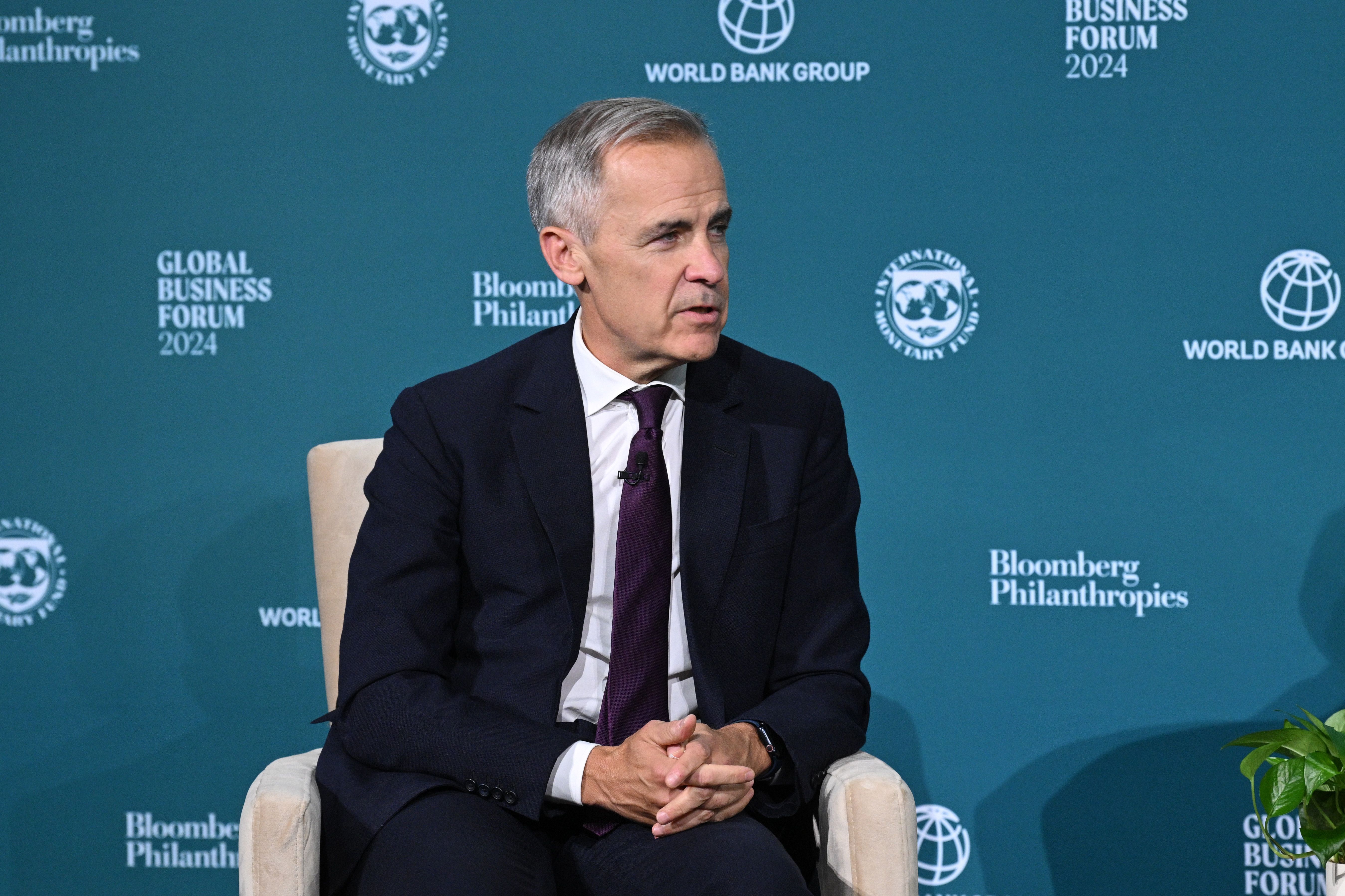 Mark Carney speaks seated on a chair with a Bloomberg Philanthropies backdrop
