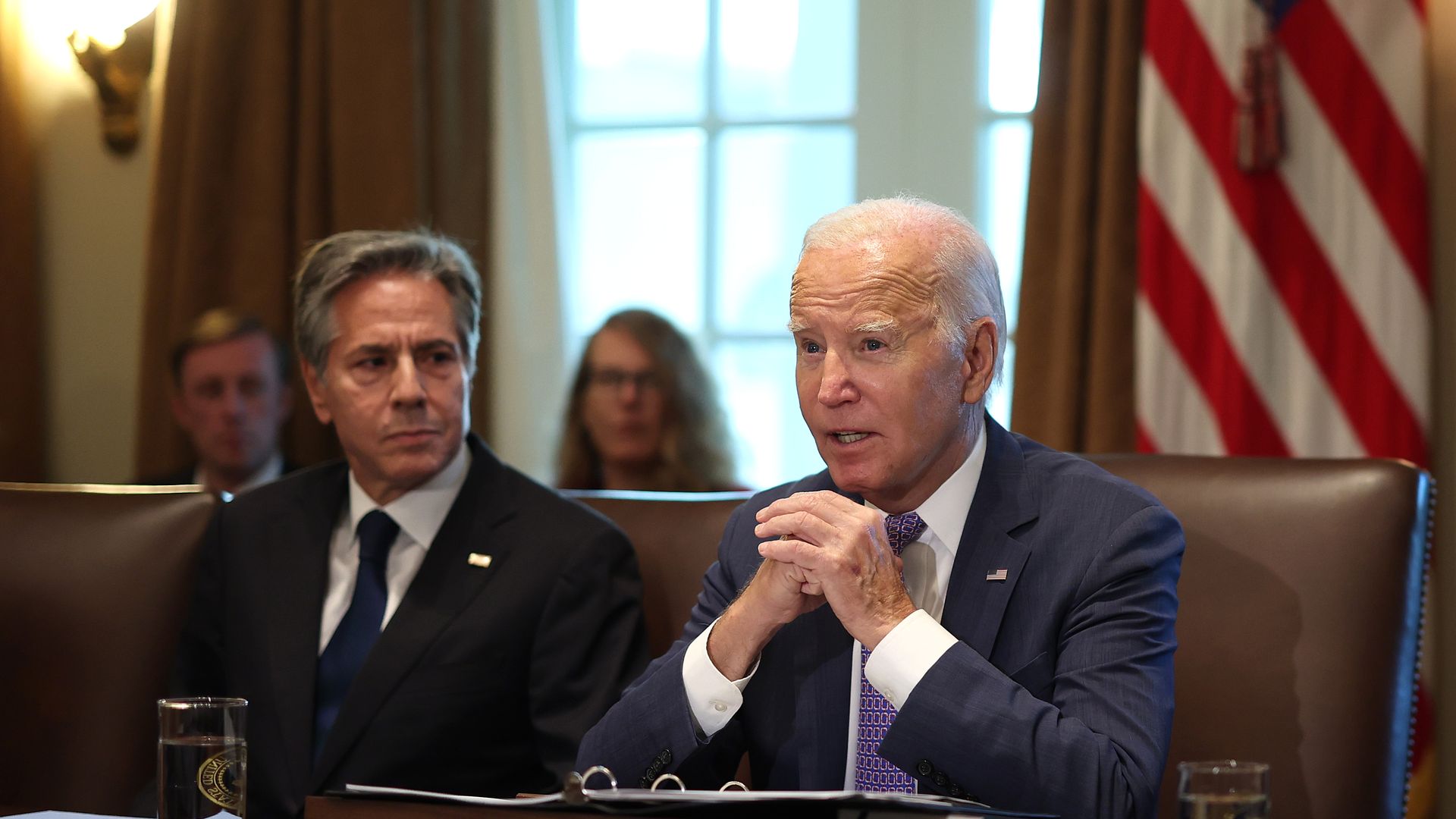 President Biden sits in a brown chair at a Cabinet meeting, with Secretary of State Antony Blinken. left.