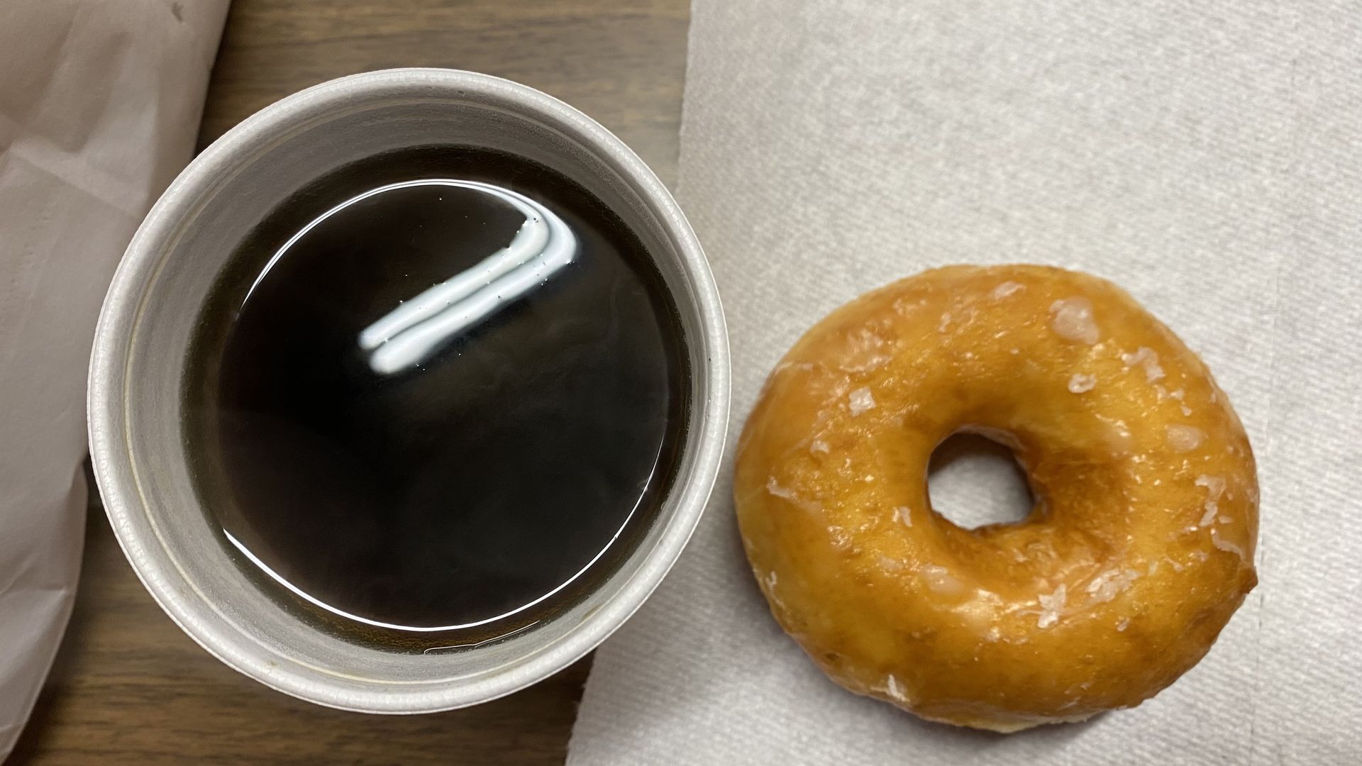 A photo of a donut and a cup of coffee. 