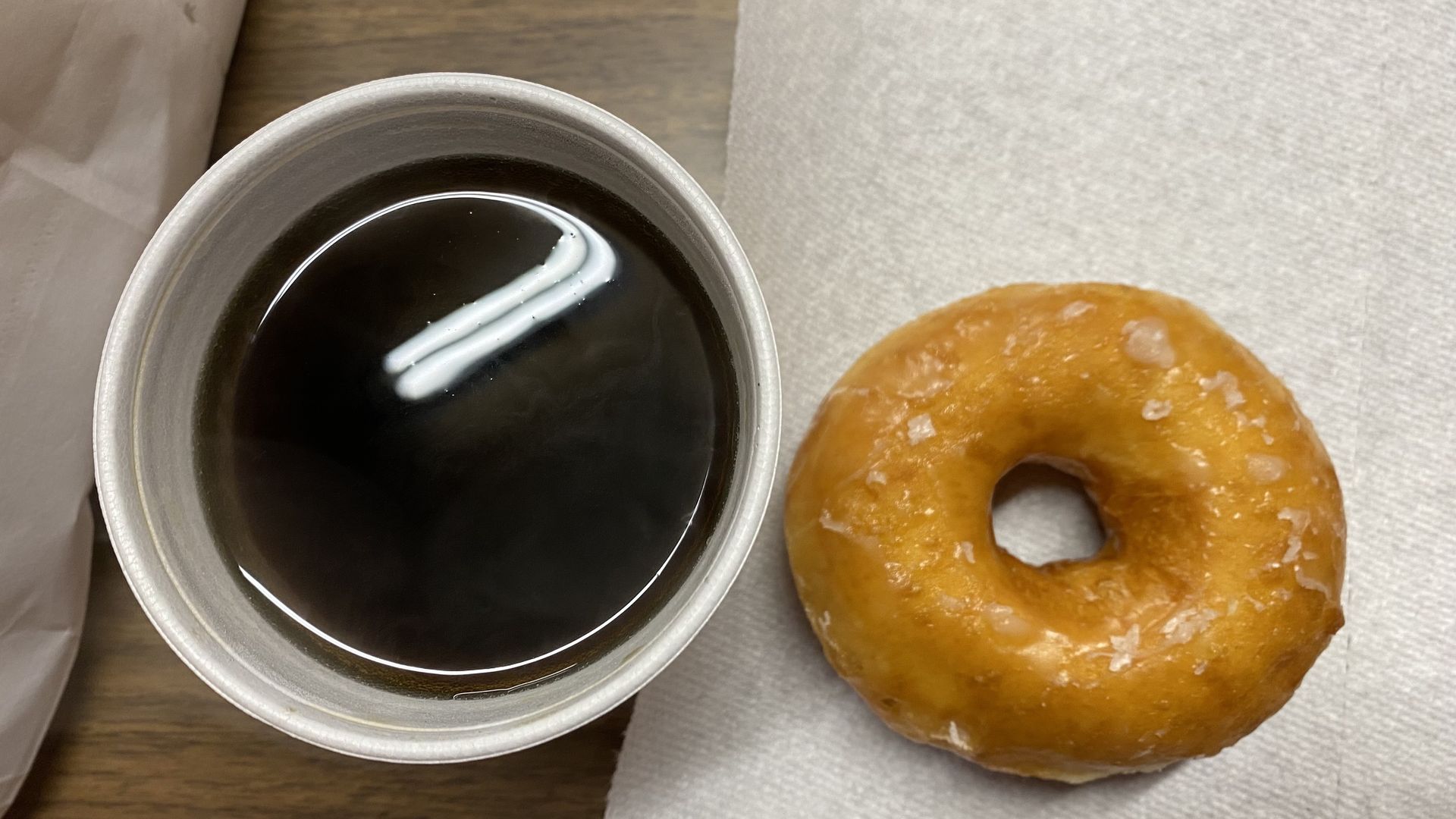 A photo of a donut and a cup of coffee.