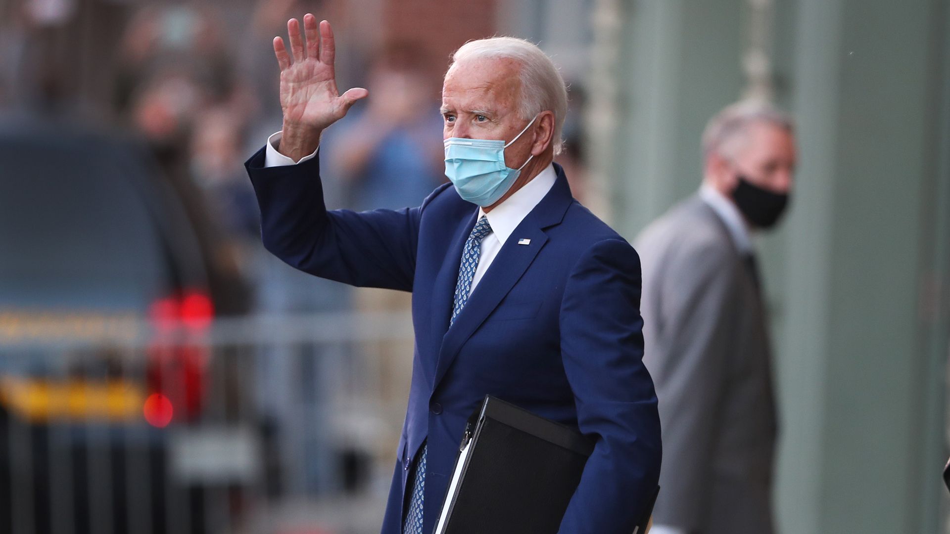 Photo of a masked Joe Biden waving as he exits a building