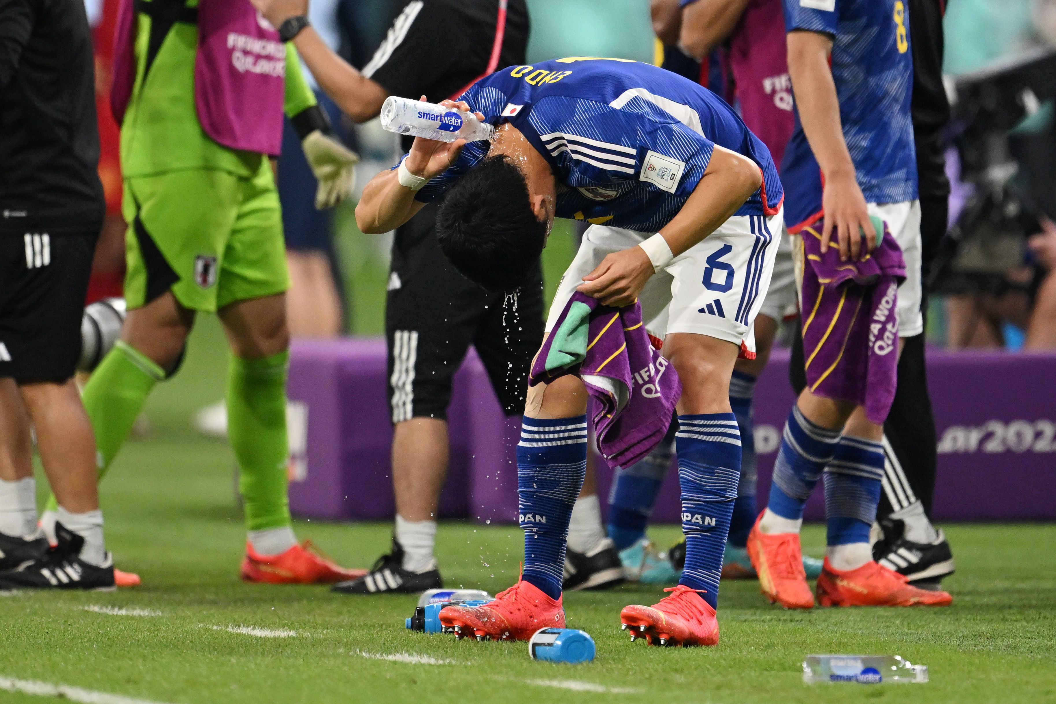 DOHA, QATAR - DECEMBER 01: Wataru Endo of Japan pours water after their 2-1 victory and qualification for the knockout stage after the FIFA World Cup Qatar 2022 Group E match between Japan and Spain at Khalifa International Stadium on December 01, 2022 in Doha, Qatar. (Photo by Clive Mason/Getty Ima