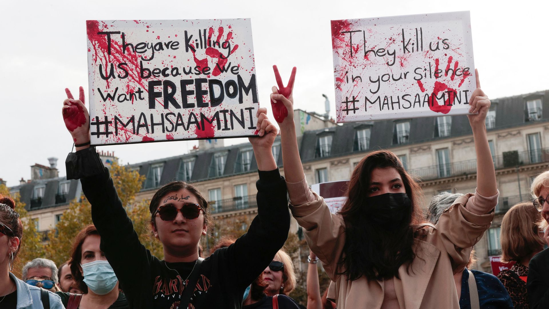 Two women hold signs protesting the Iranian government following the death of Mahsa Amini. 