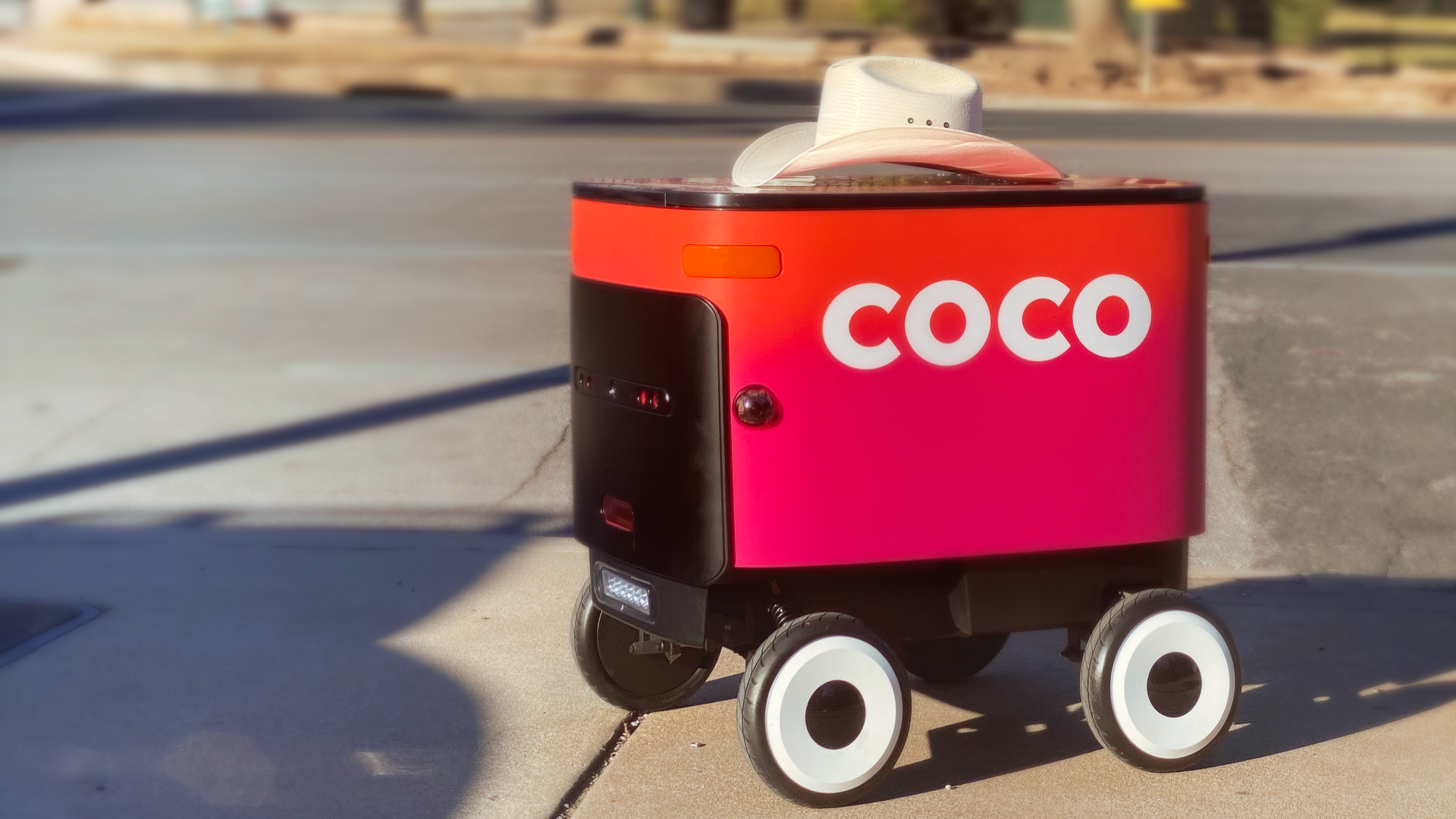 A small, wheeled Coco food delivery robot.