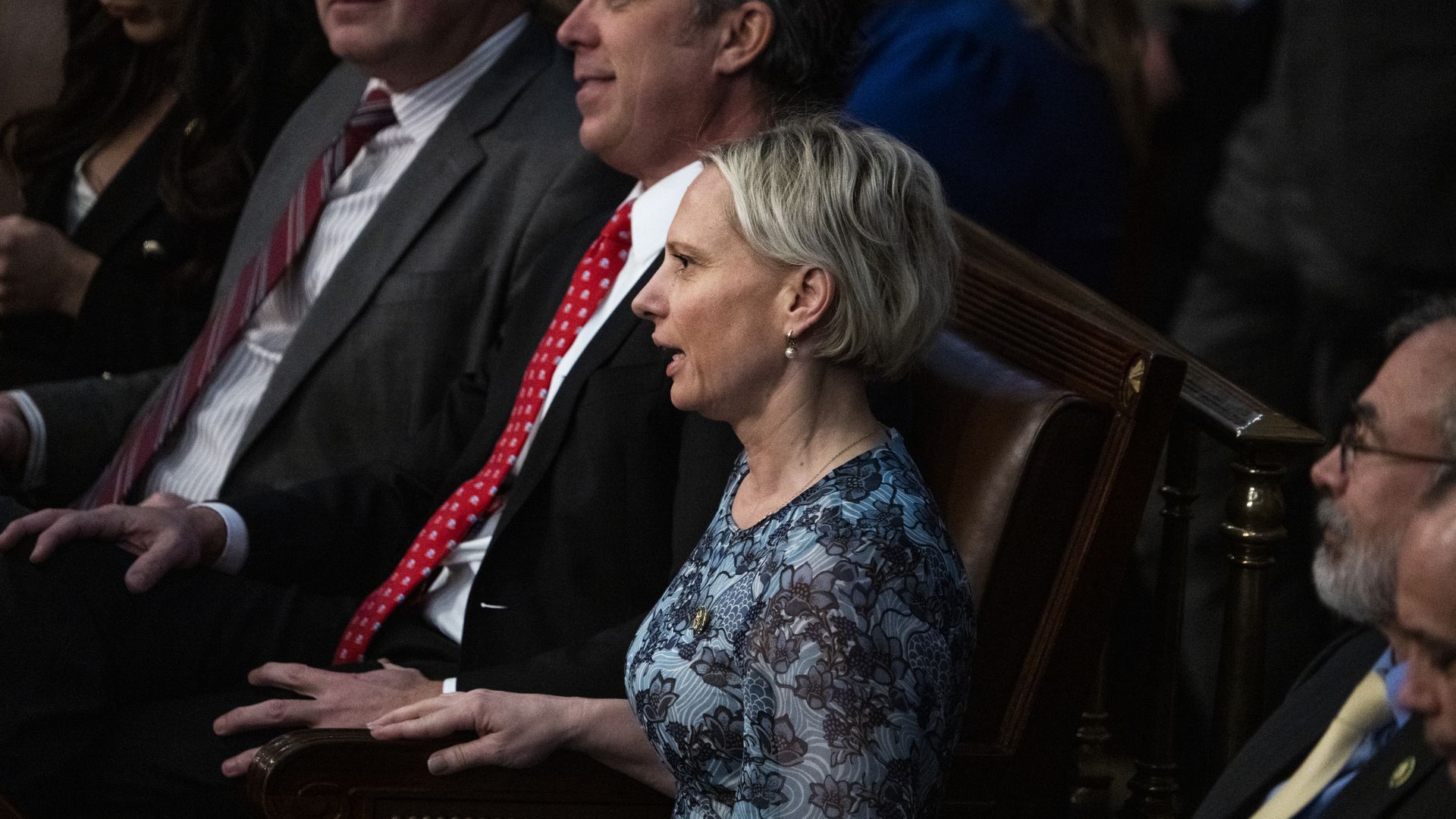 Rep. Victoria Spartz, wearing a blue dress, surrounded by colleagues in the House chamber.