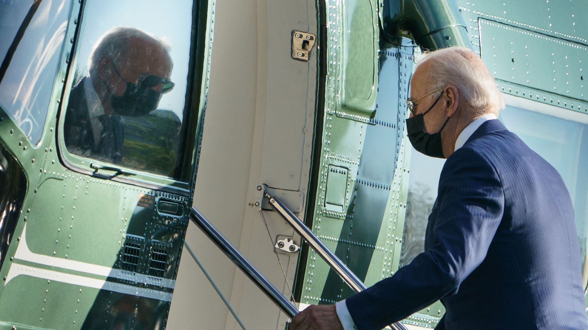 President Biden is seen in reflection as he boards Marine One.
