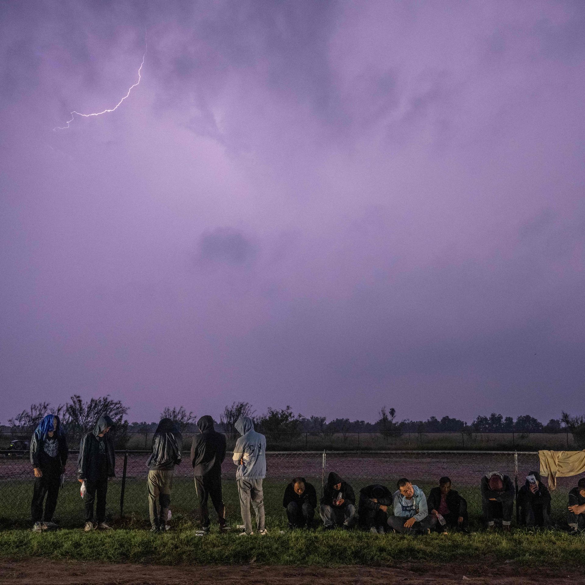 Migrants wait in the rain after turning themselves over to US Border Patrol agents after crossing over from Mexico in Fronton, Texas 