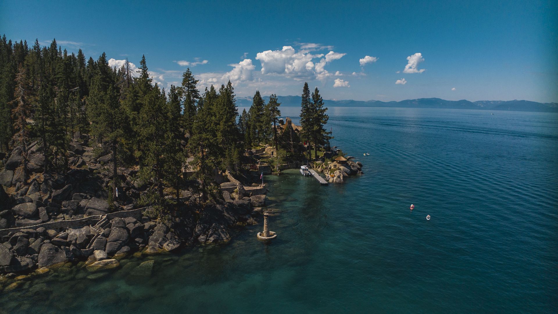 An aerial view of a lake surrounded by a mountain of trees