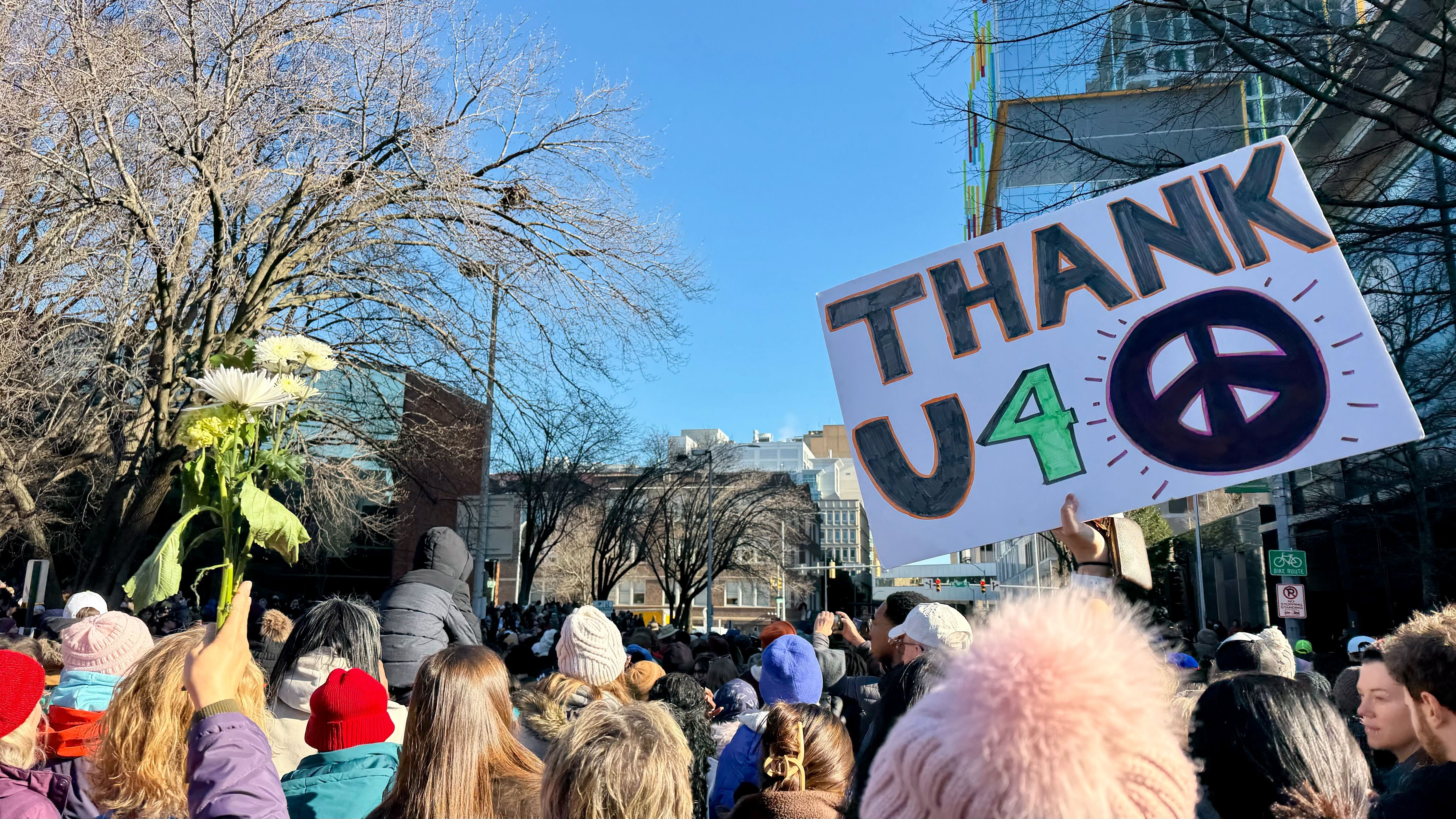 people hold flowers and signs 