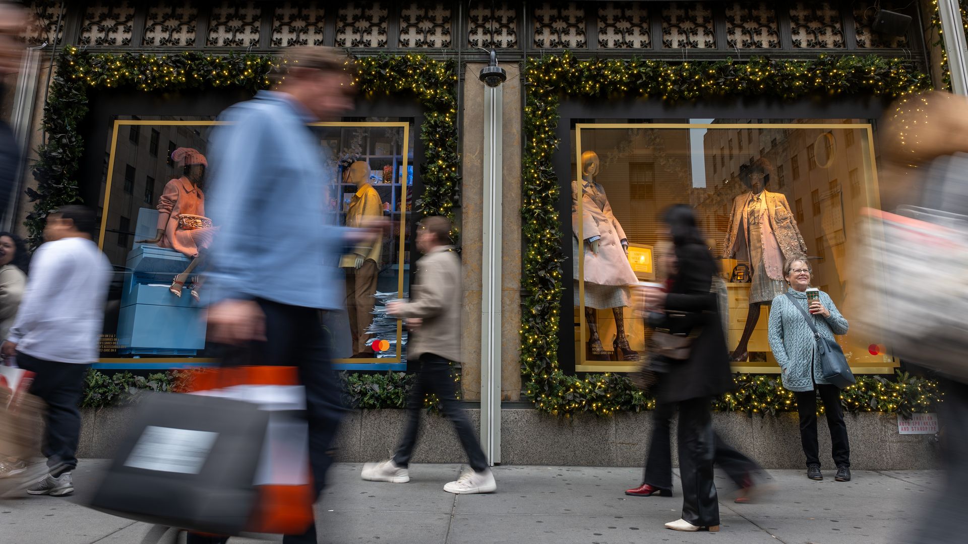Blurry images of NYC holiday shoppers walking quickly past a store window.