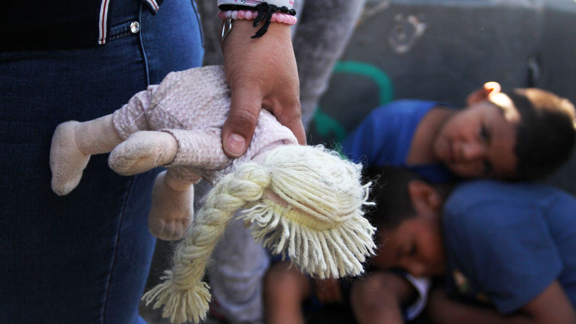 A Mexican woman holds a doll next to children at the Paso Del Norte Port of Entry, in the US-Mexico border in Chihuahua state, Mexico on June 20, 2018.