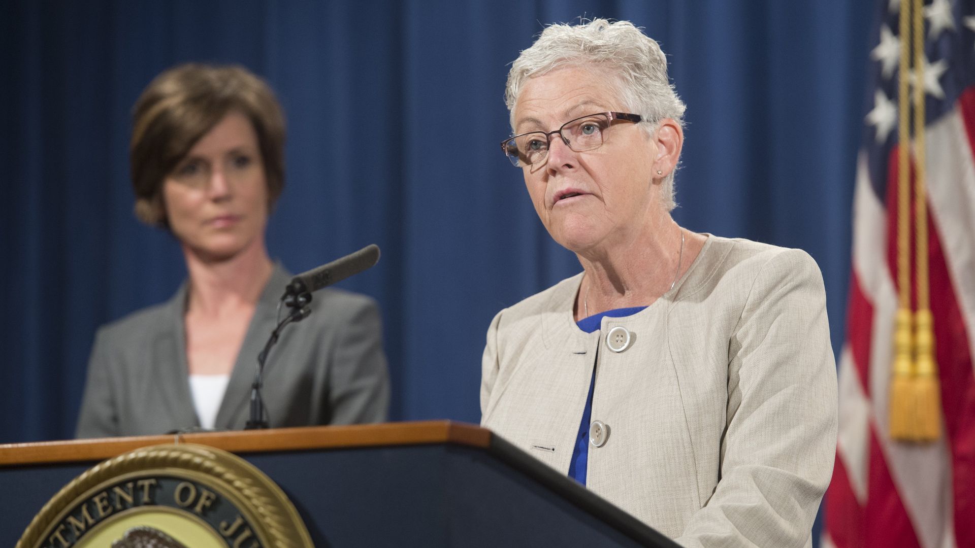 Photo of Gina McCarthy speaking behind a podium with an American flag to her back
