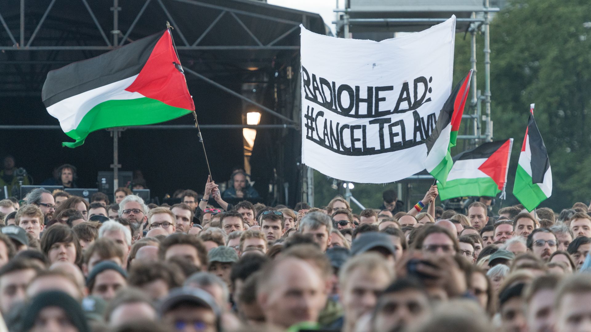 Protestors hold up a banner calling for Radiohead to cancel a show in Israel.