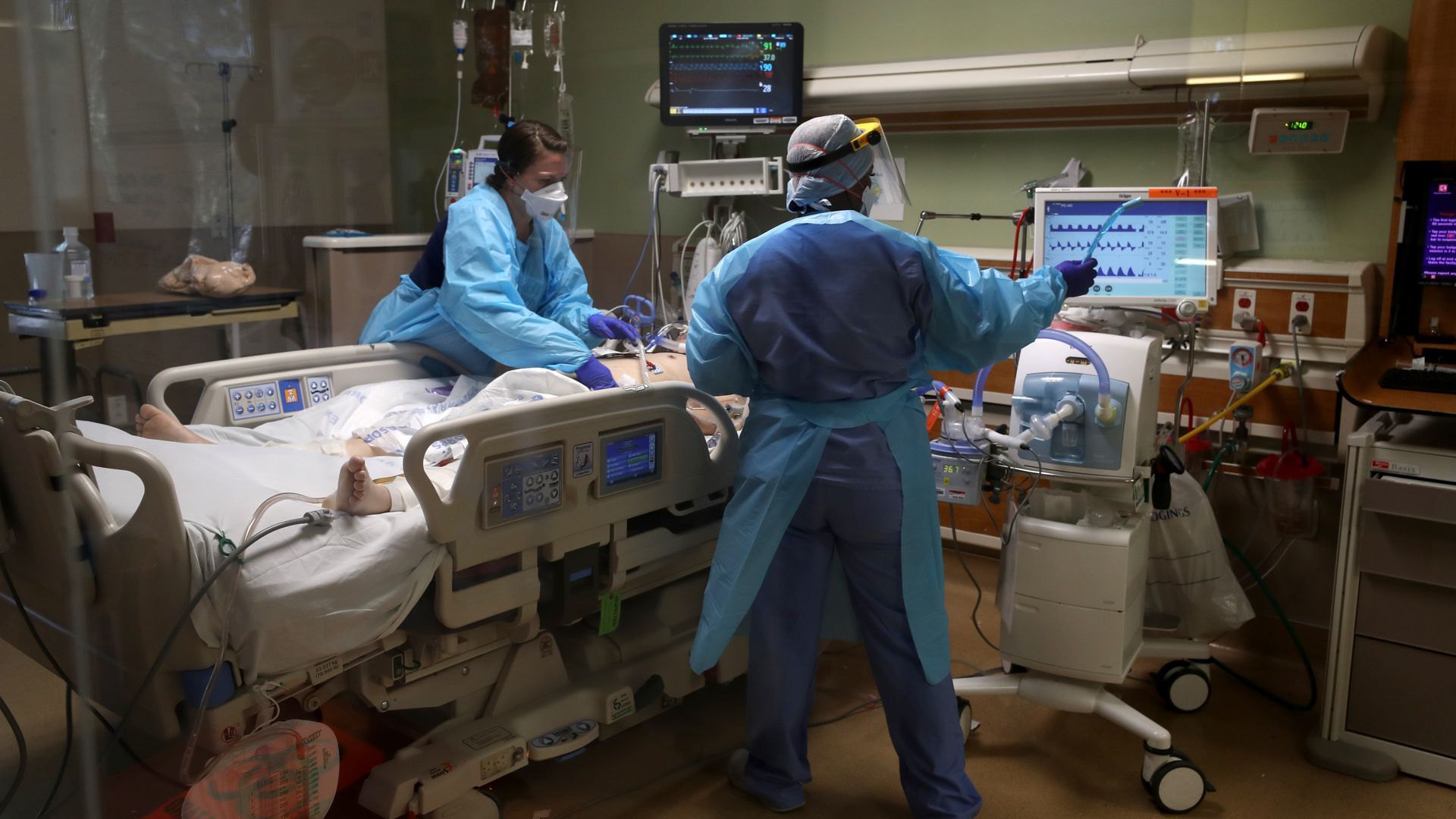 In this image, two doctors stand over a hospital bed