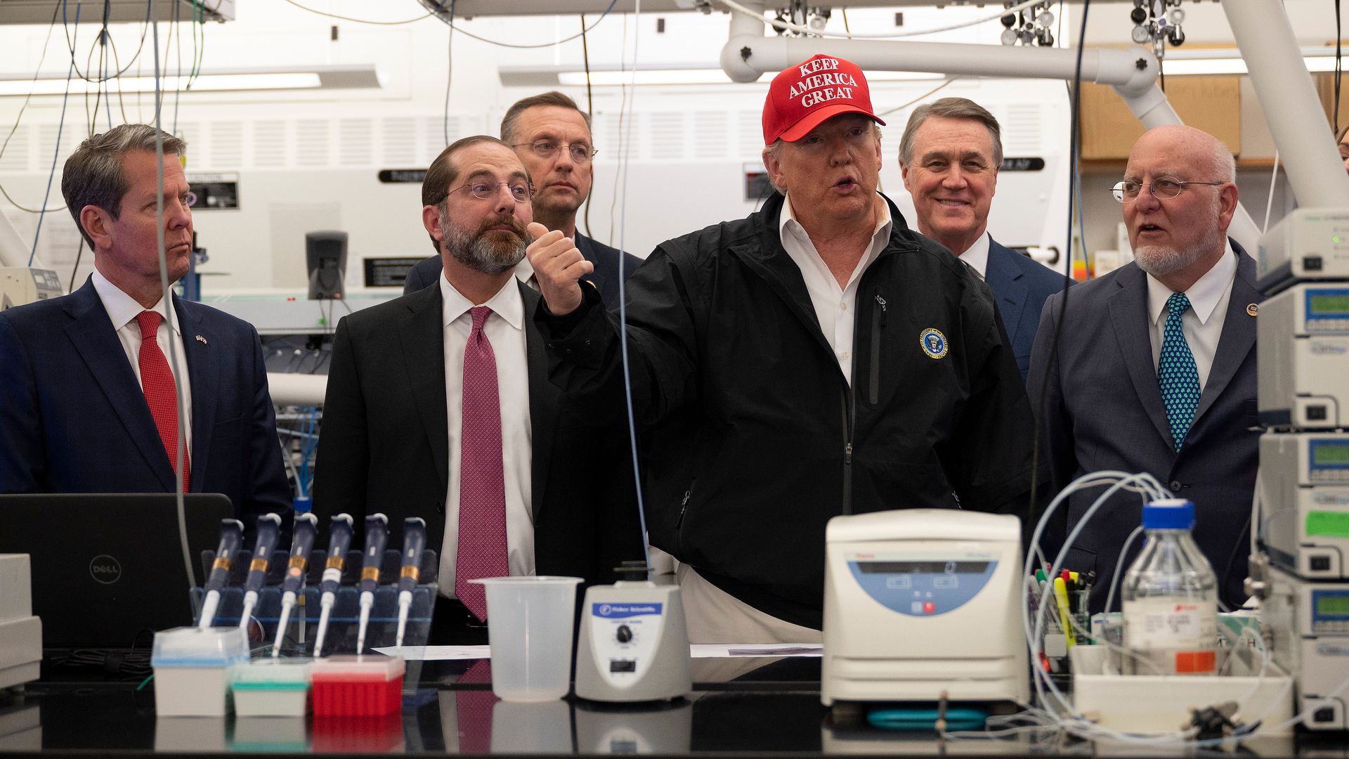 In this image, Trump stands in the middle of a group of men and talks