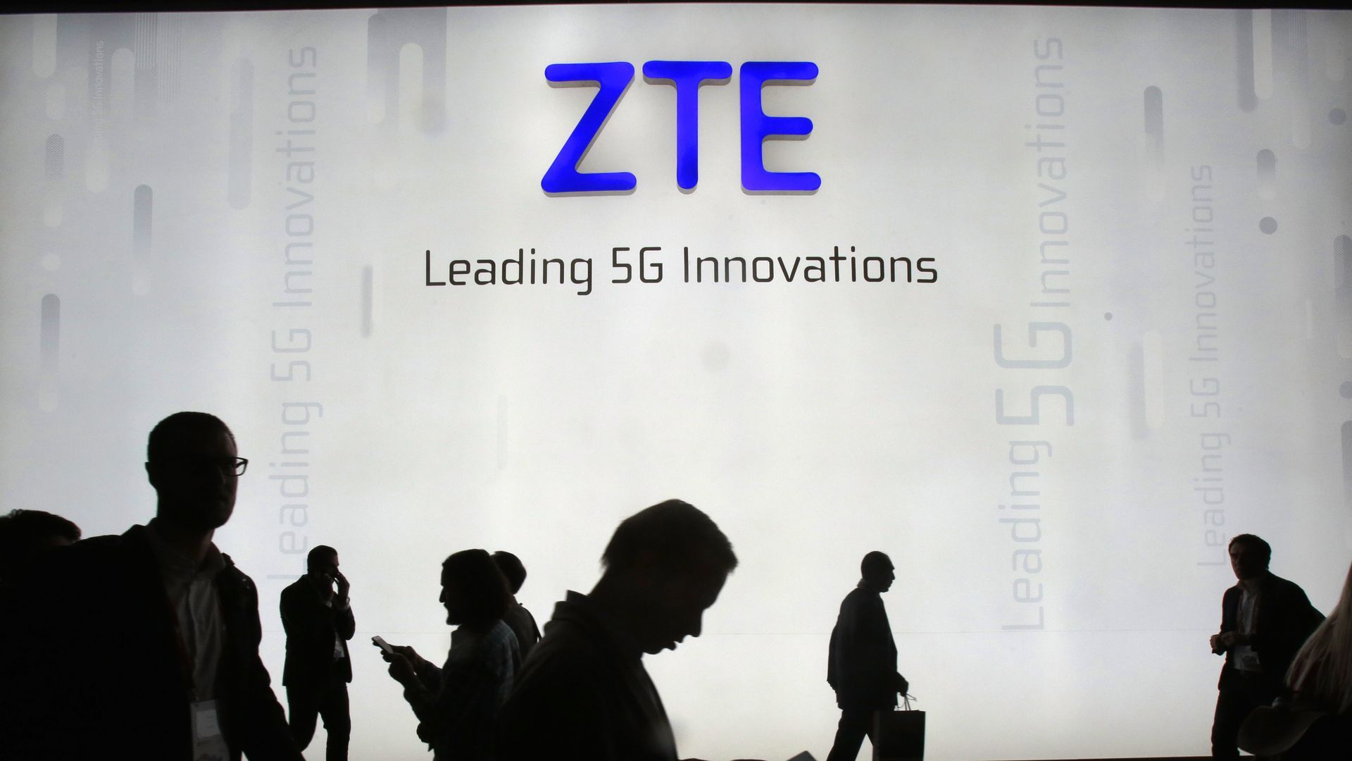 ZTE logo on wall with shadowy human figures below