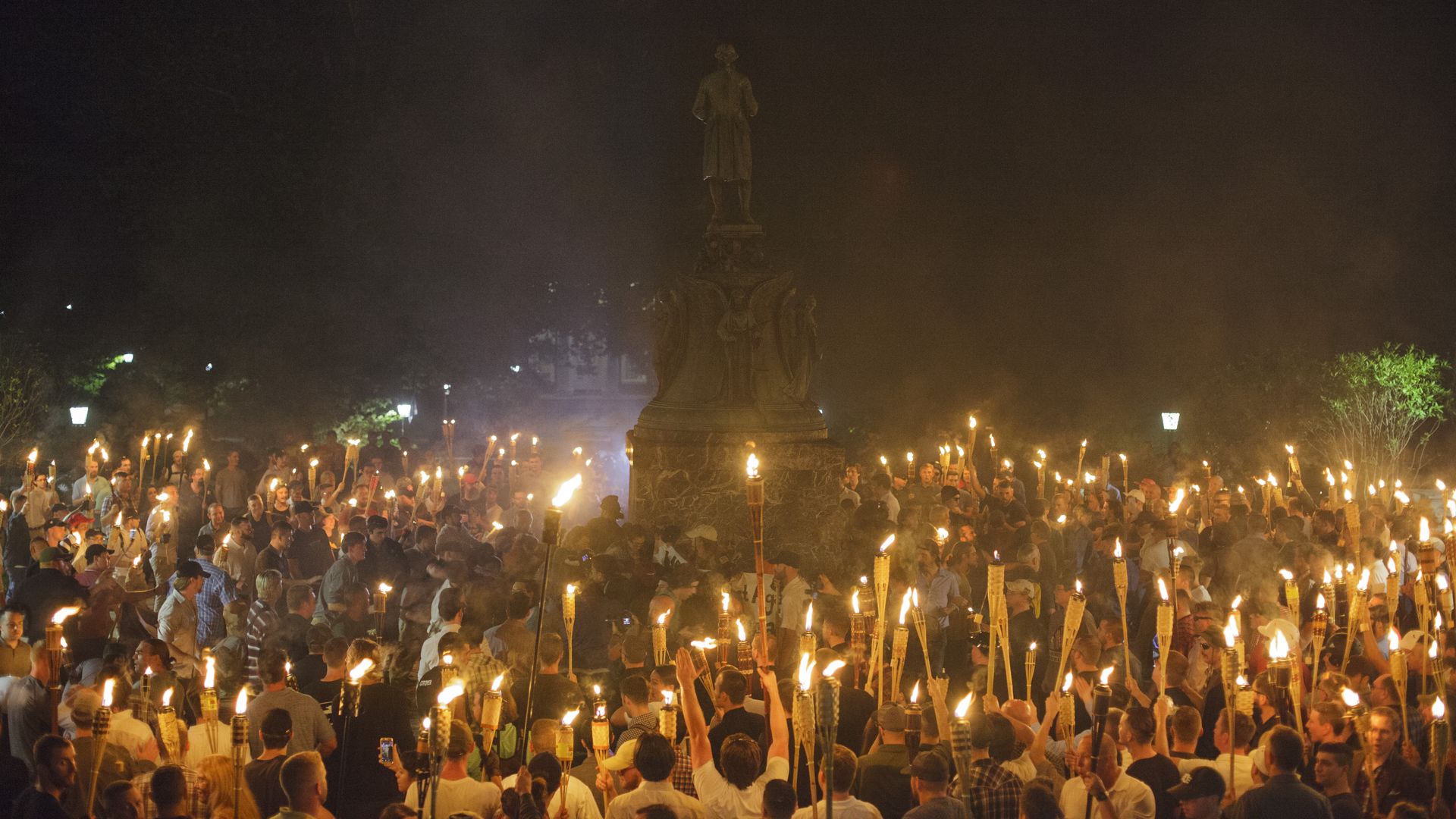 This image shows a crowd of torch-carrying people surrounding a statue of Thomas Jefferson at night.