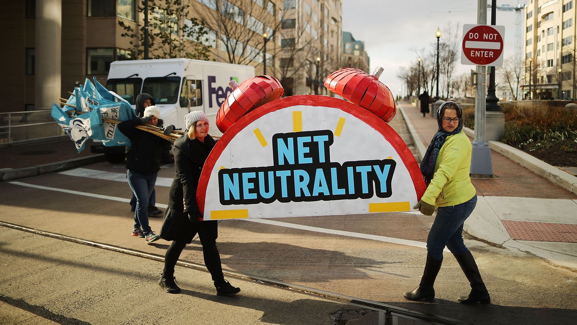 Two people carry a large imitation alarm clock that says "net neutrality"