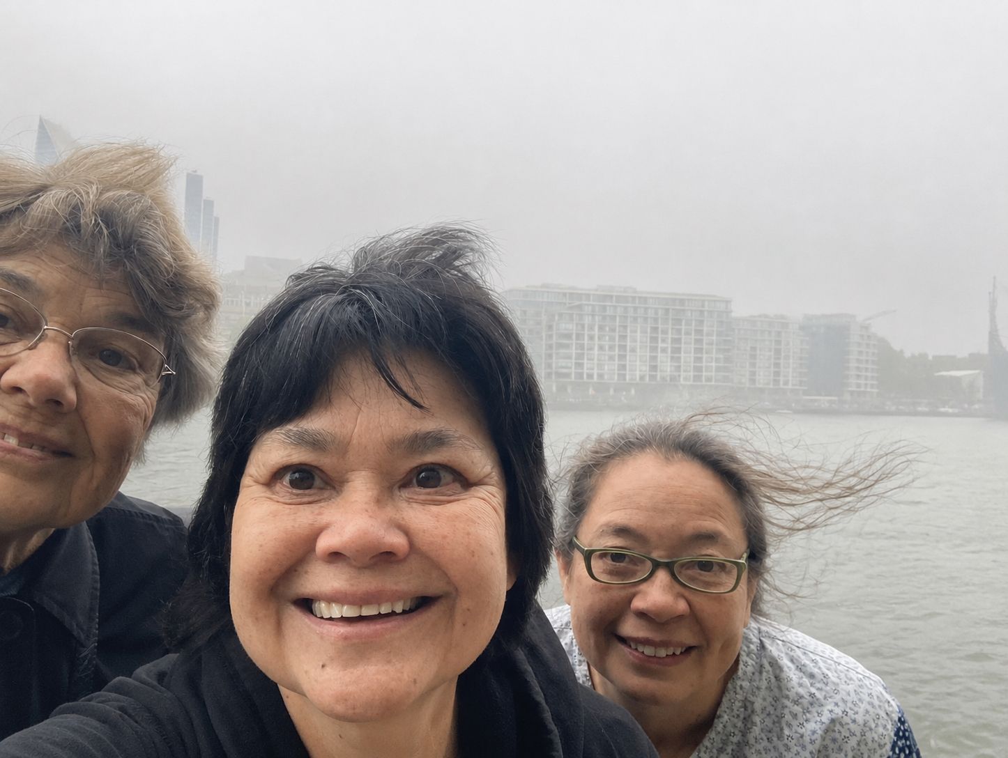 Three women take a selfie in front of the Thames. 