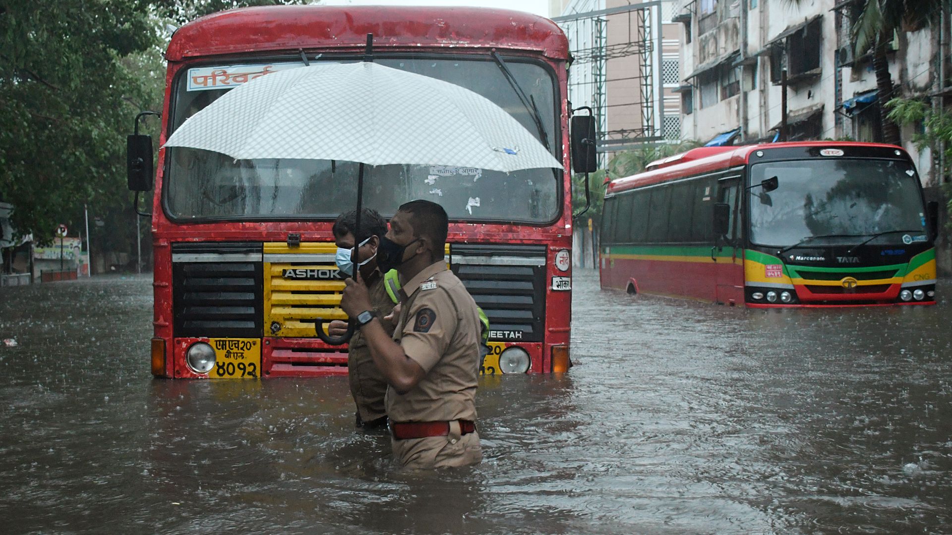 A policeman helps a public transport driver to cross a flooded street due to heavy rain caused by cyclone 'Tauktae' in Mumbai.