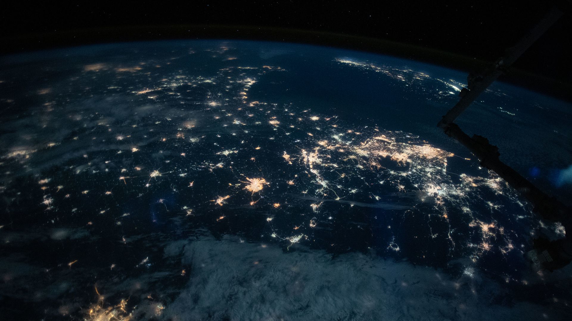 Bright lights illuminated on Earth seen from orbit at night.
