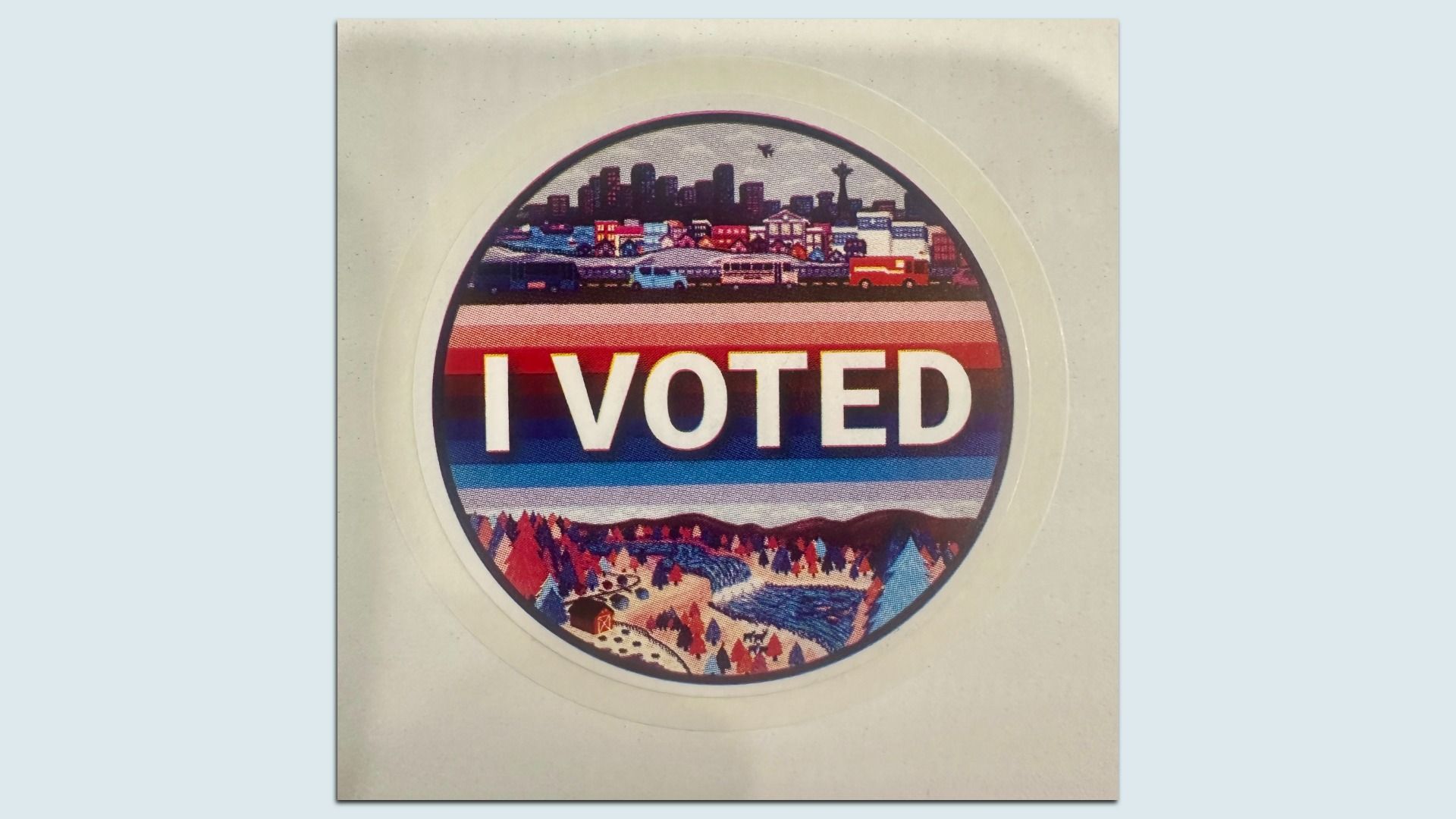 Circular badge with a beige outer ring and a rainbow-striped center that reads I VOTED; a city skyline sits above and snowy hills below inside the circle.