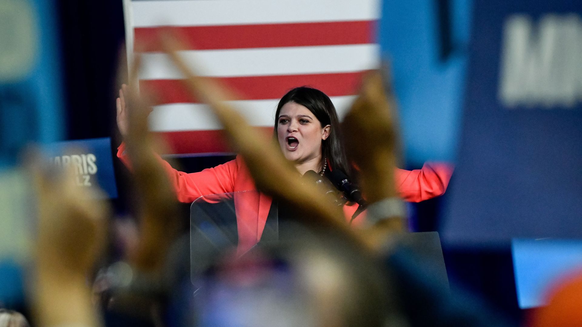 Rep. Haley Stevens, wearing a salmon blazer in front of blue signs.