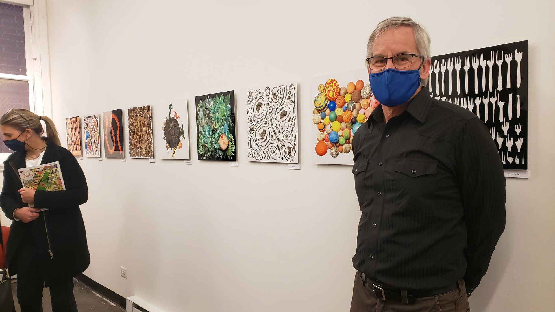 A photo of a man standing in front of artwork. 