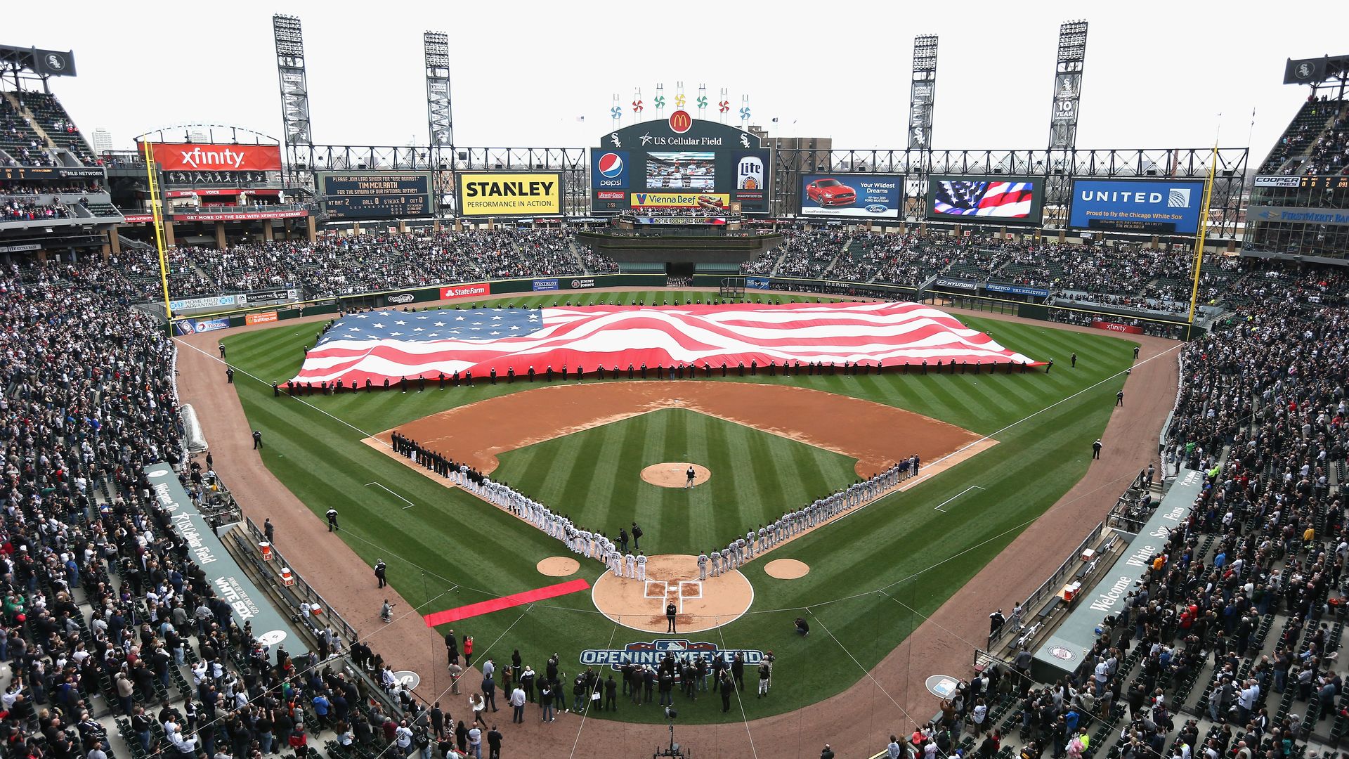 Photo of a huge American flag on the field of a baseball game. 