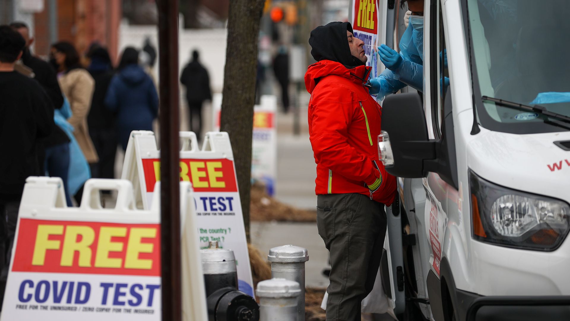 A man in a red jacket stands by a truck and gets a nose swab for a COVID test.