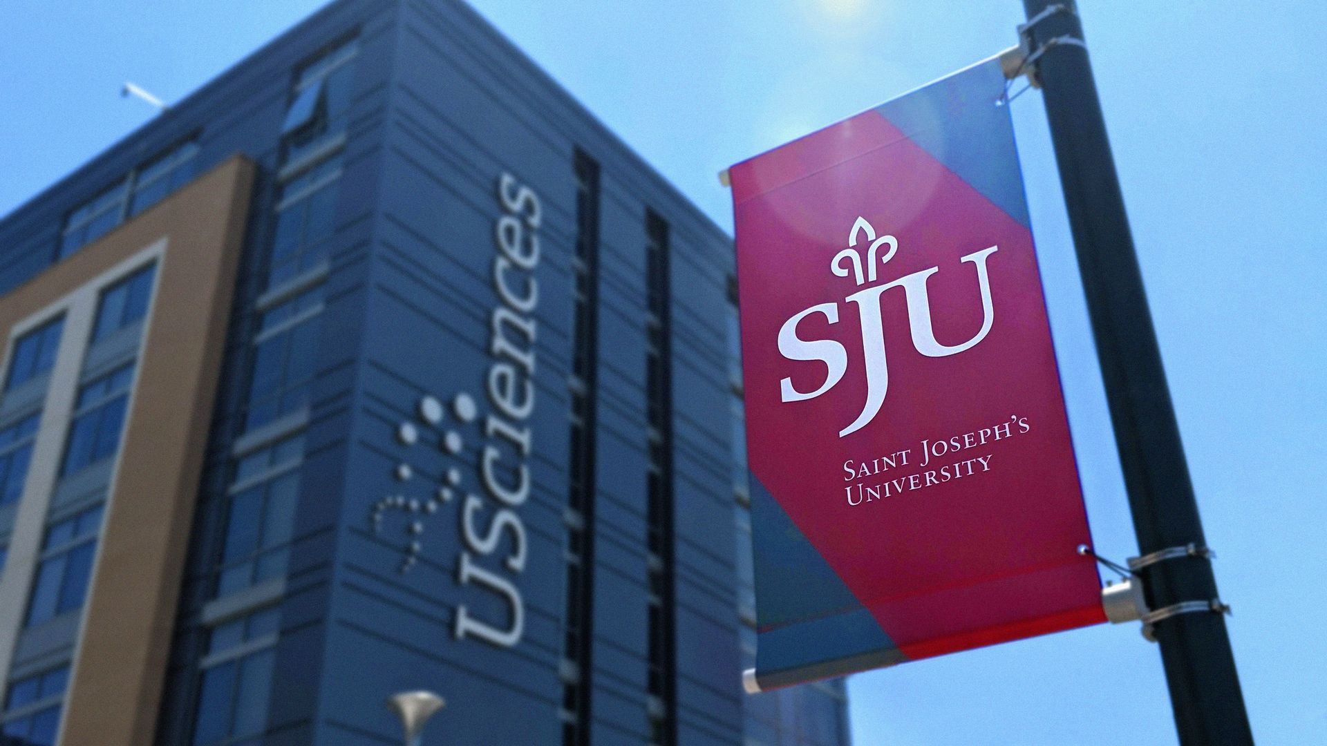 A Saint Joseph's University banner hangs in front of a University of the Sciences building