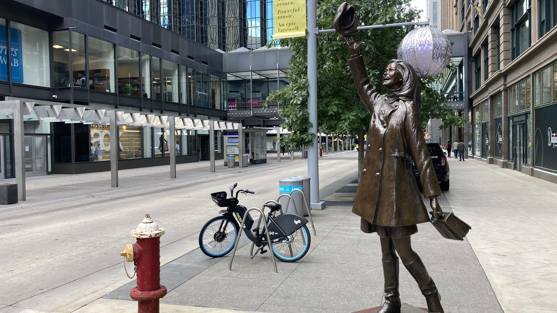 Mary Tyler moore statue, with downtown in the background. Nicollet mall is empty 